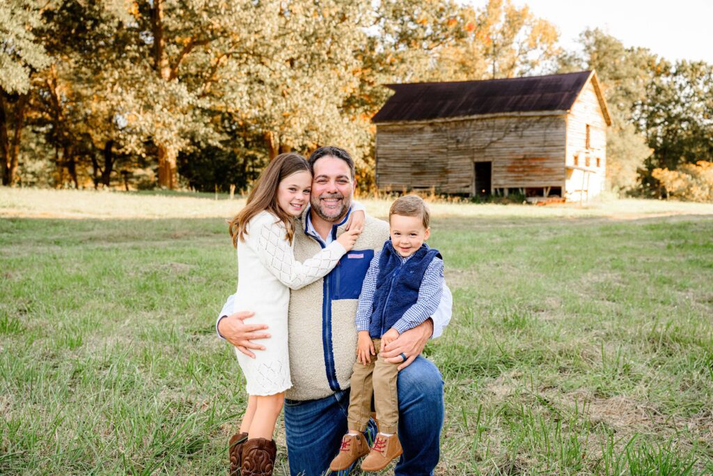 Dad cuddled in together with both of his kids during in a fall background