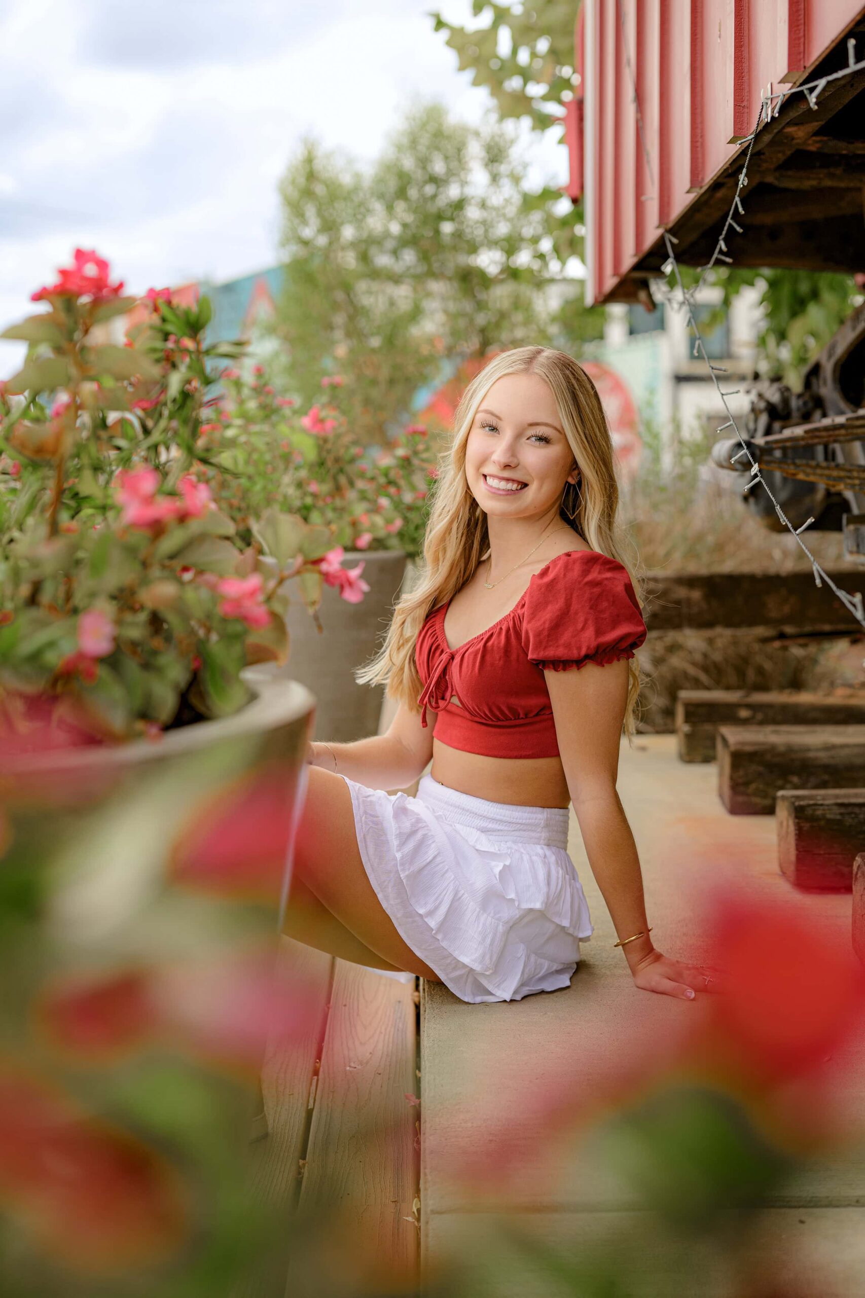 charlotte grad sits with her hand behind her wearing a white skirt and red crop top in rock hill sc