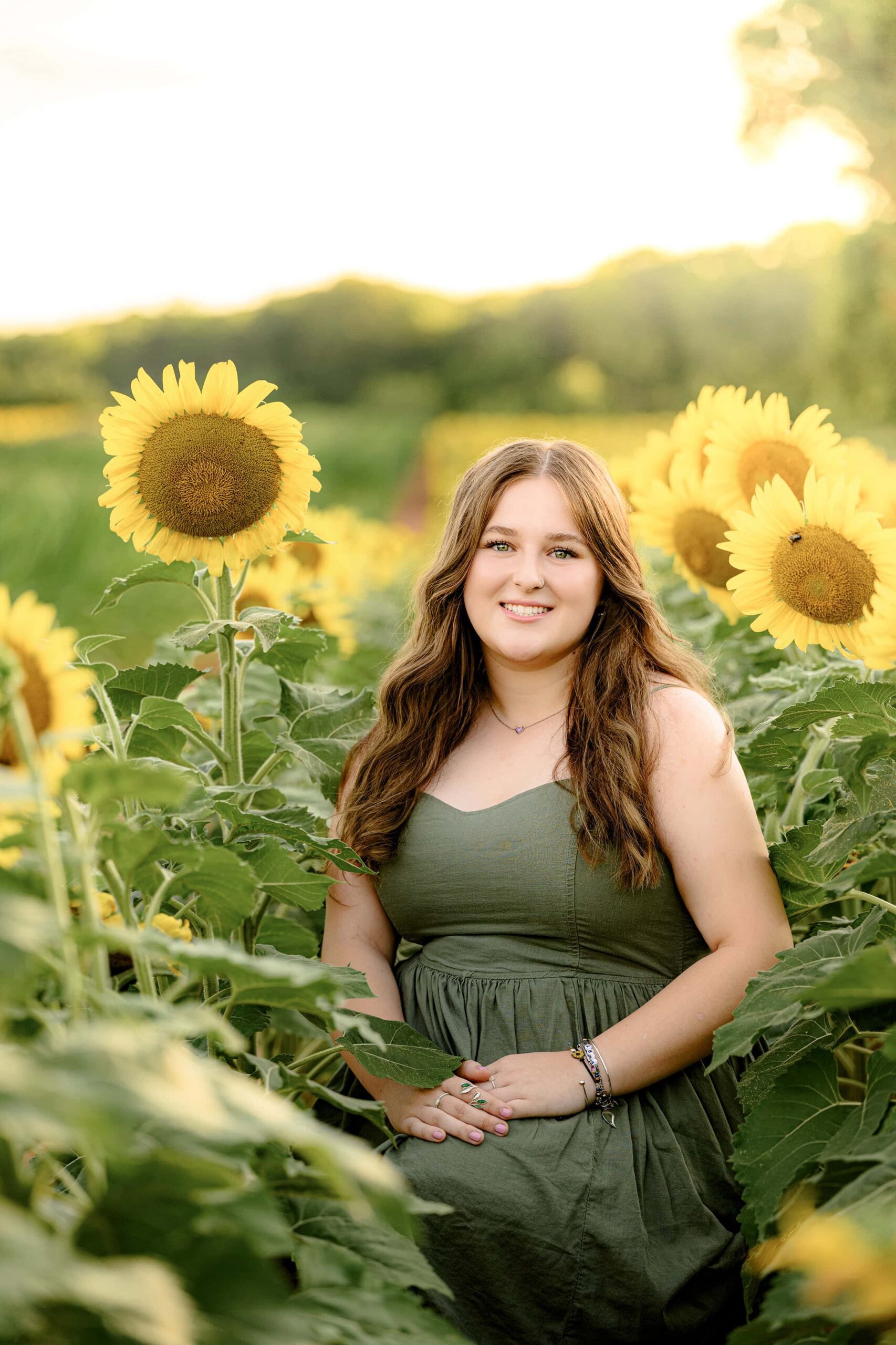 Cuthbertson senior graduate with long dark hair sittiing in a field in a green dress