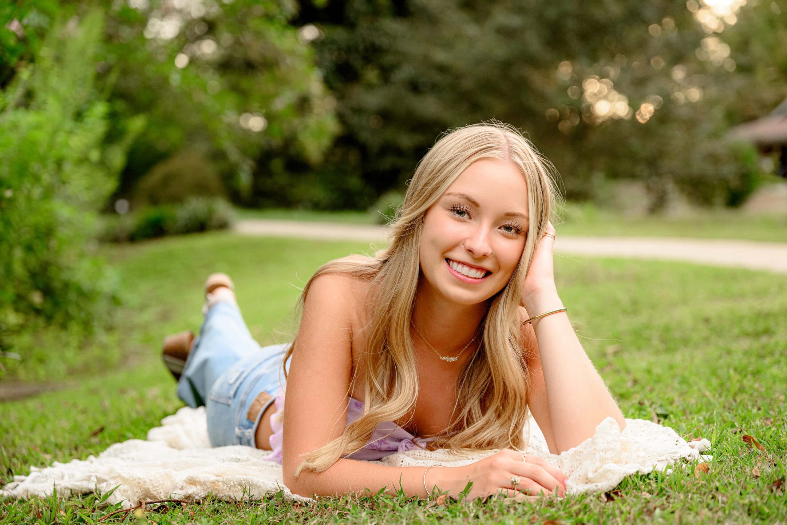 Waxhaw NC senior poses with her hand on her hair while laying down in a south carolina park during her essential experience grad session