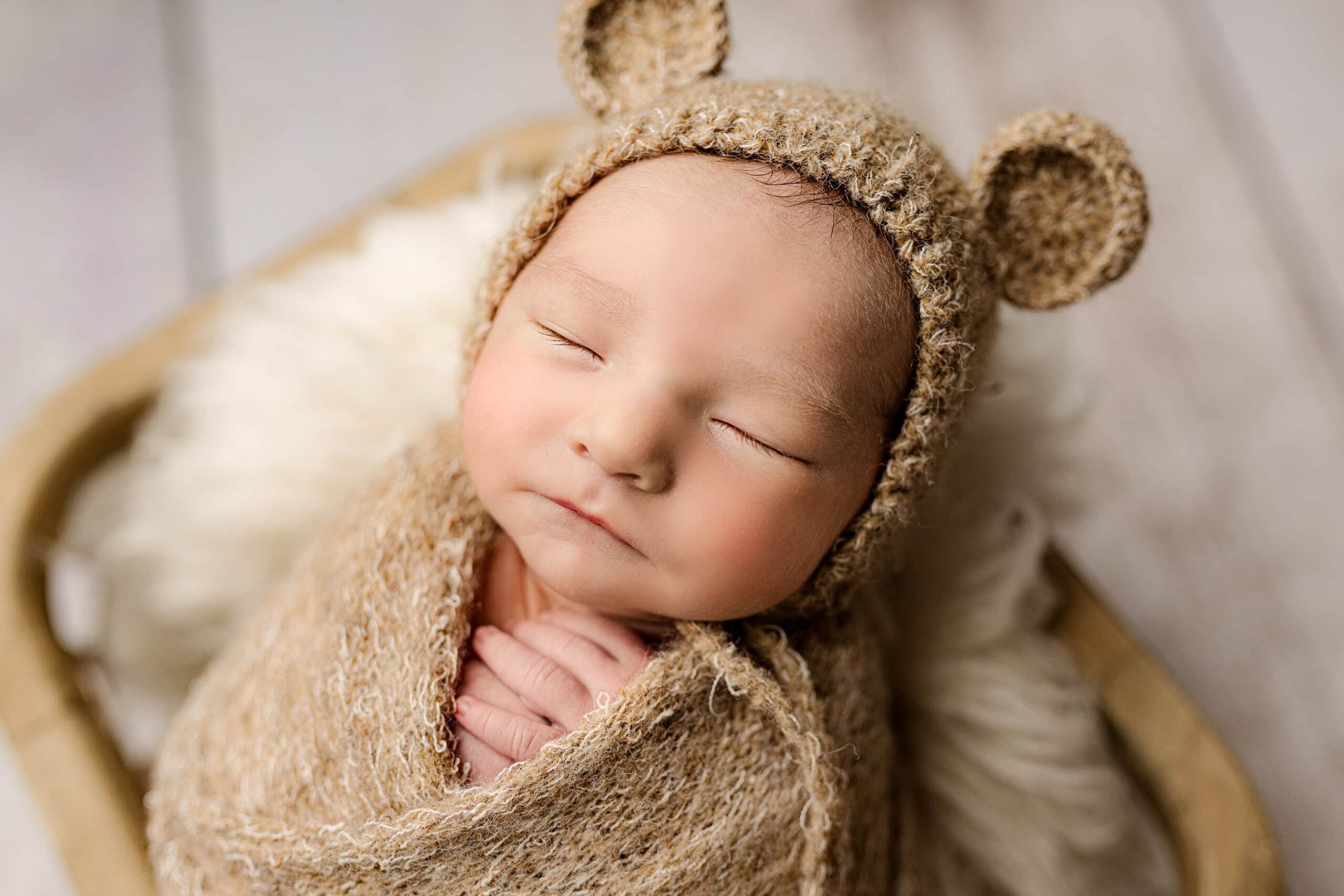 close up image of newborn boy wearing a knit hat with ears that matches his wrap