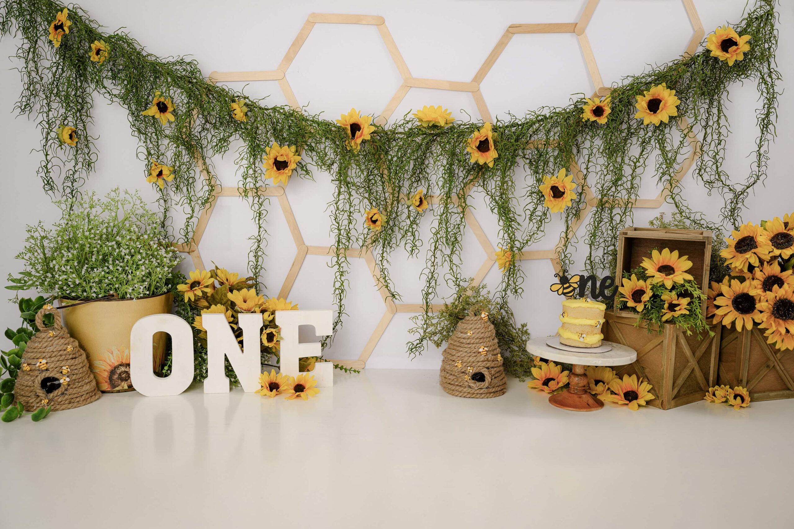 custom creative cake smash set up filled with sunflowers, handmade bumble bee hives and tiny bumblebees perfect for a little ones cake smash session in the waxhaw, nc studio