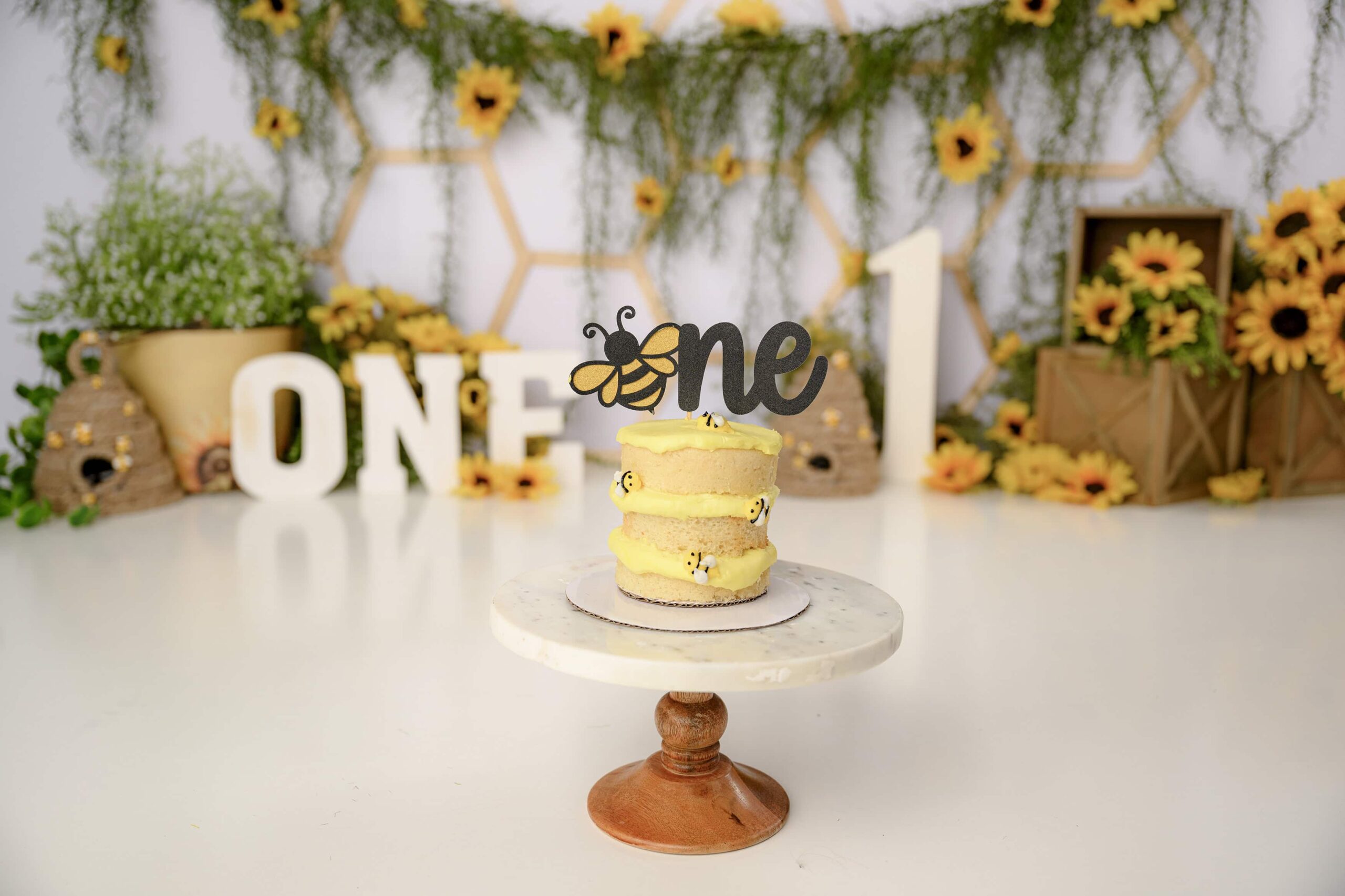 Custom 3 tiered cake with dripping icing and little bumblebees placed on it perfect for this themed Happy Bee Day Cake Smash Session.
