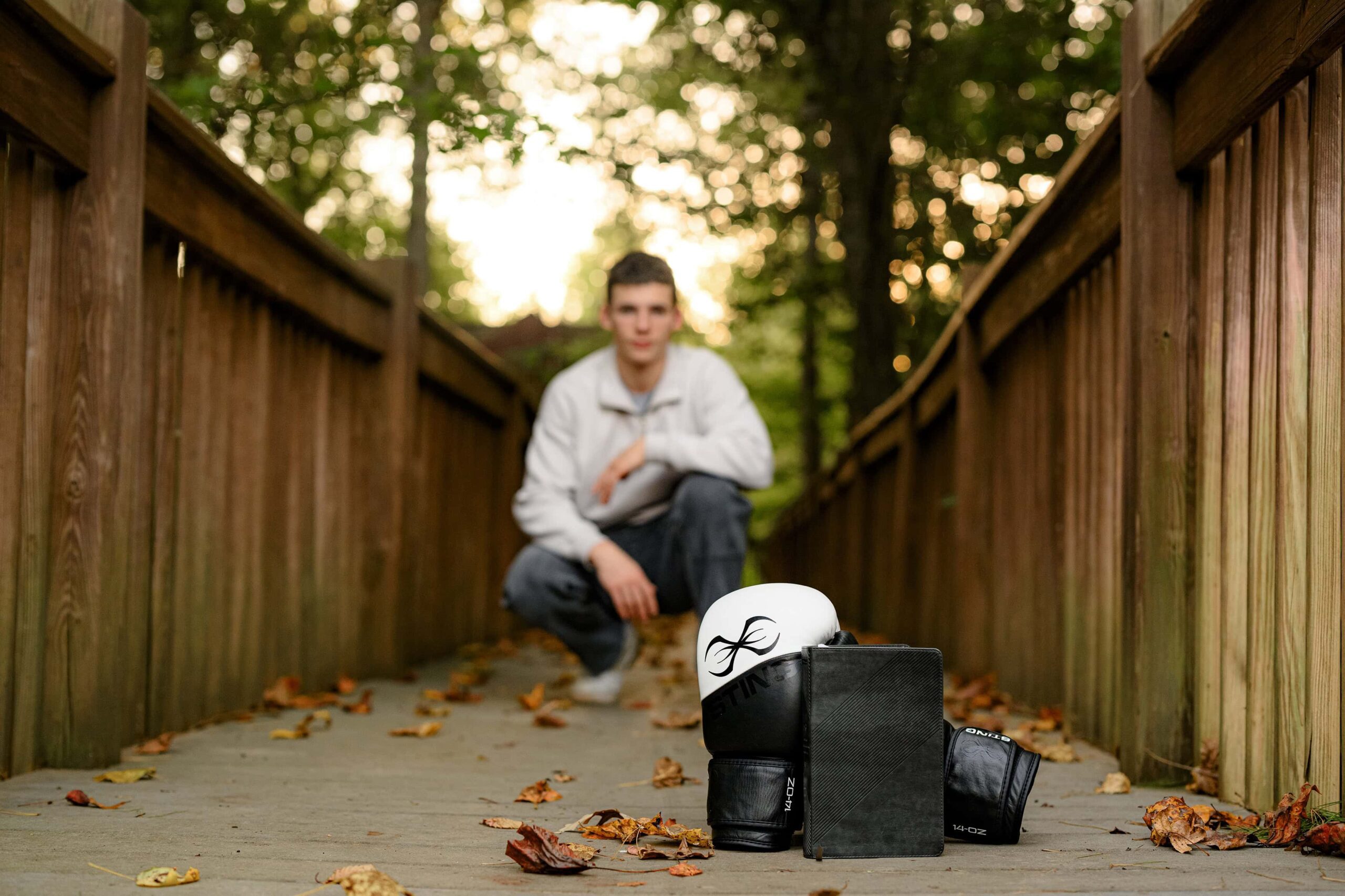 senior boy is behind a prop set up with his boxing gloves and a bible as his personalized props