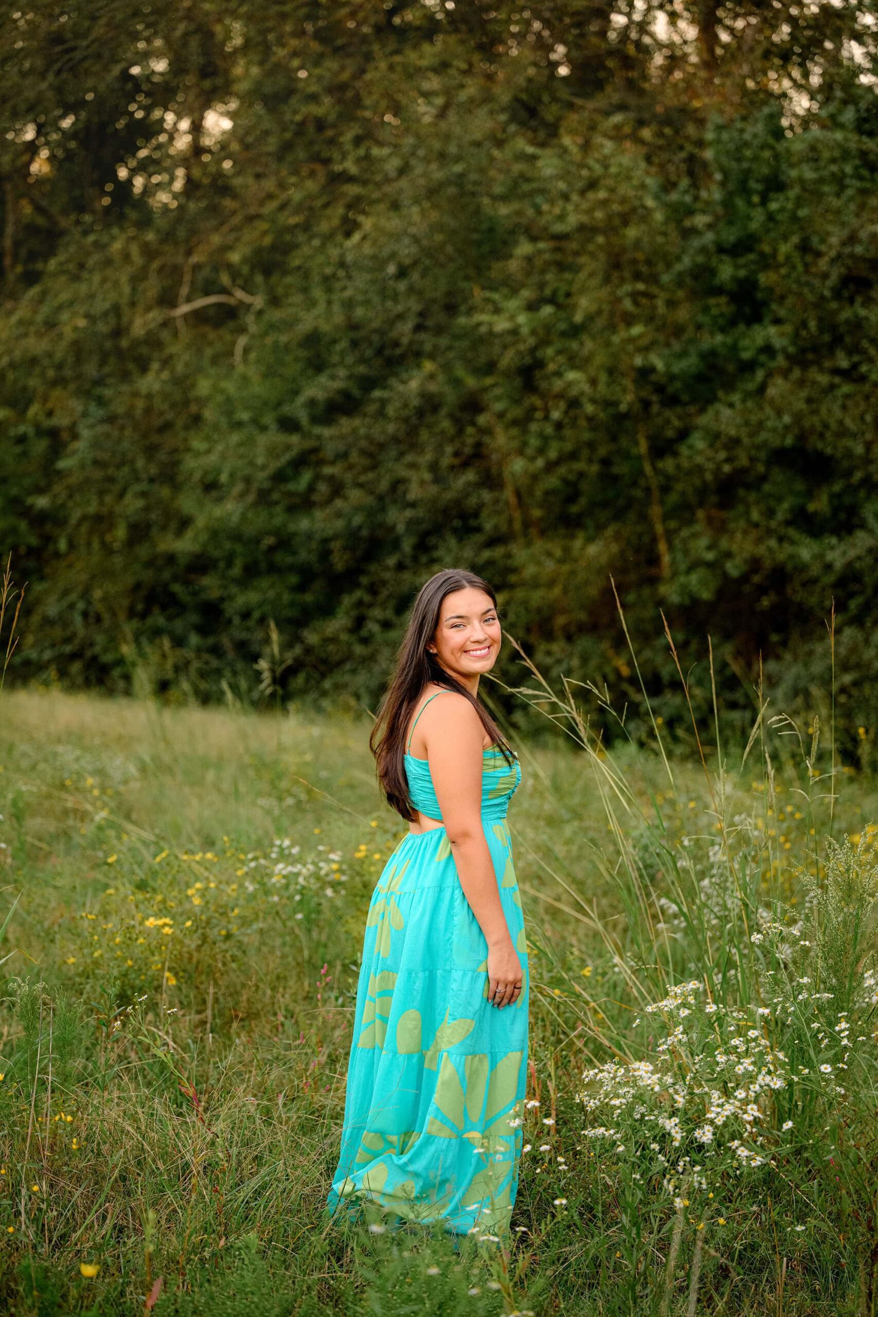 The teal dress on this senior girl pops as she stands in a waxhaw, nc field during her grad photoshoot