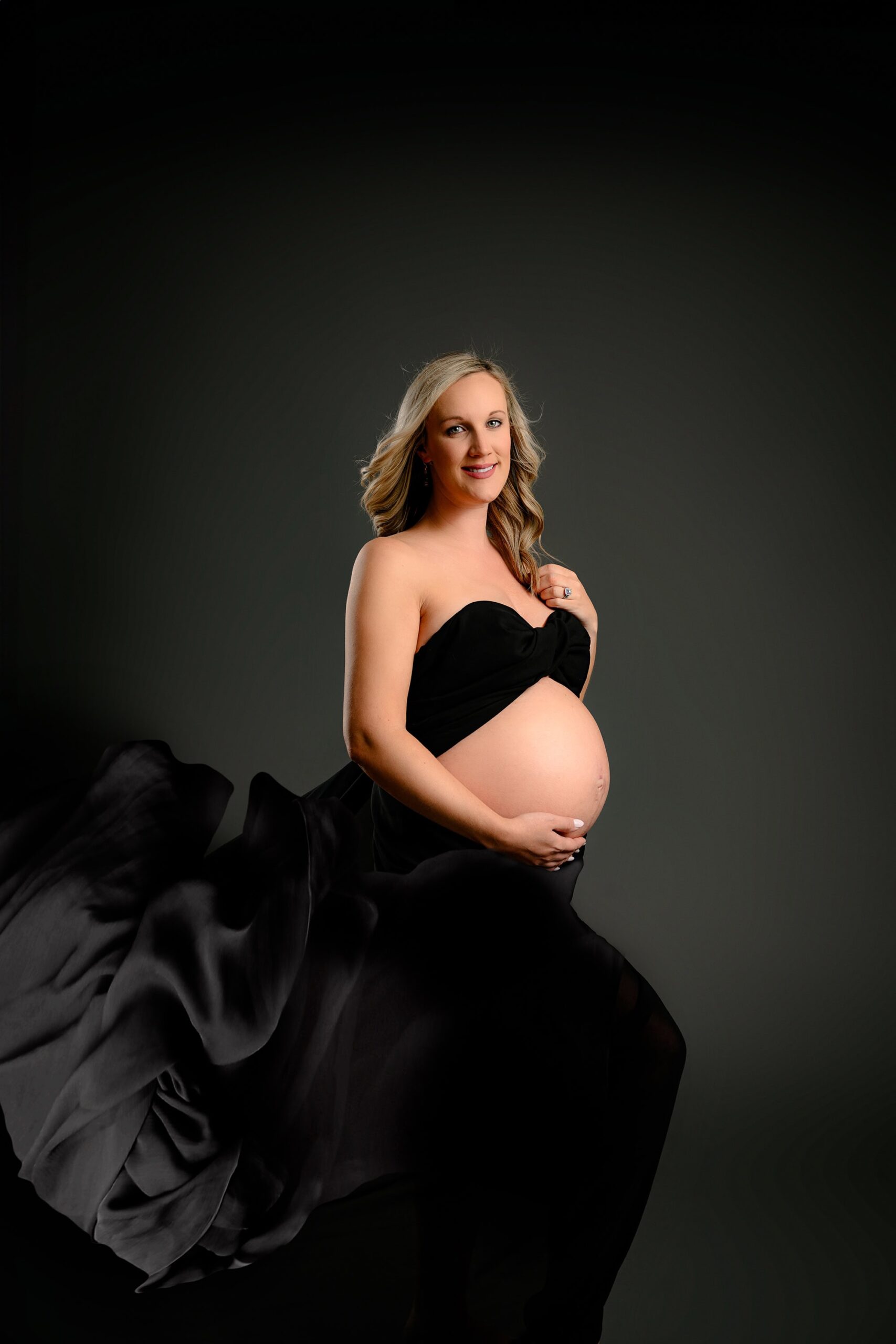Wrapped in sheer black chiffon, this mama beautifully highlights her growing belly. With one hand in her hair and the other cradling her bump, the portrait captures a perfect balance of strength and softness.