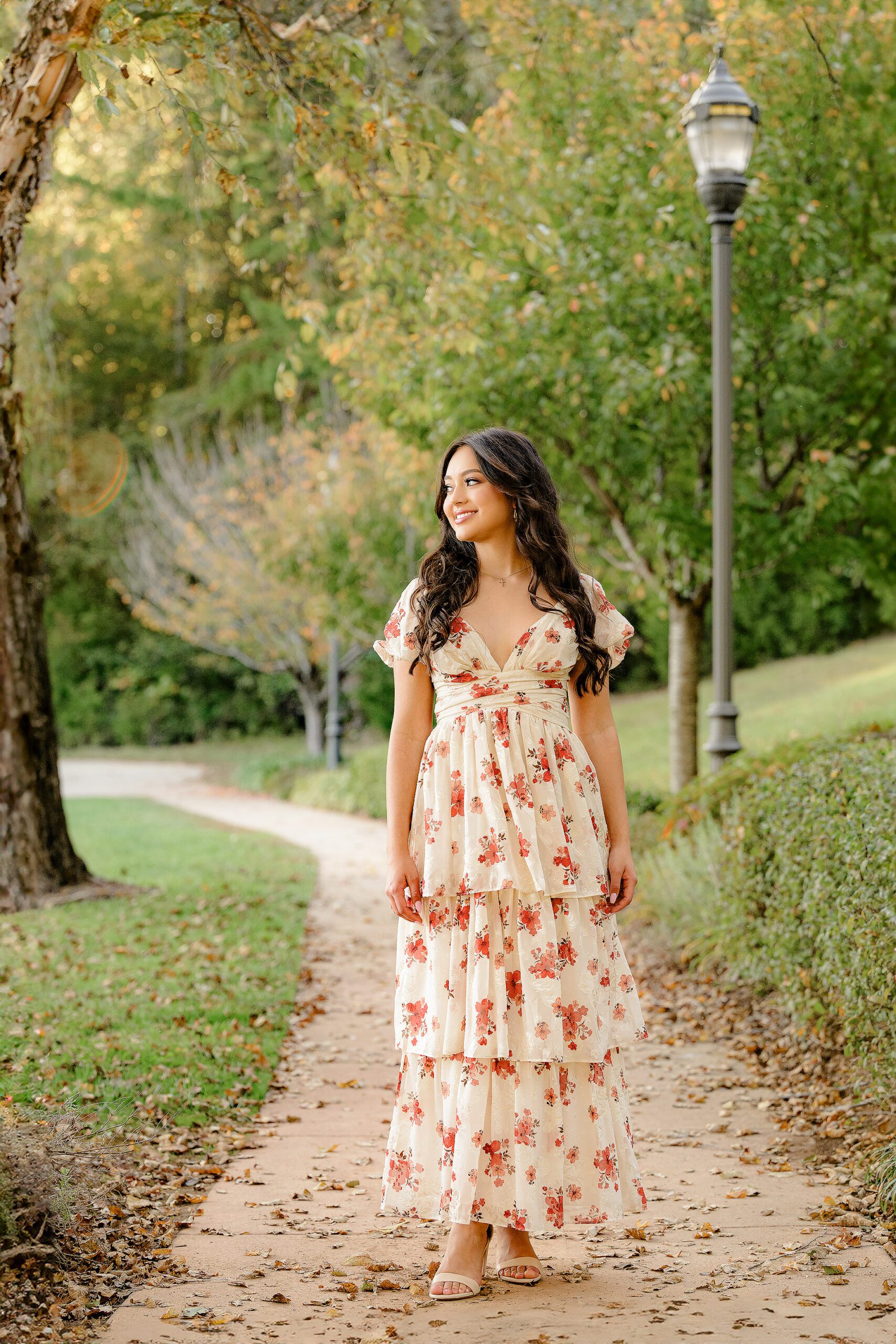 Class of 2025 graduate stands looking off in the distance In a flower dress