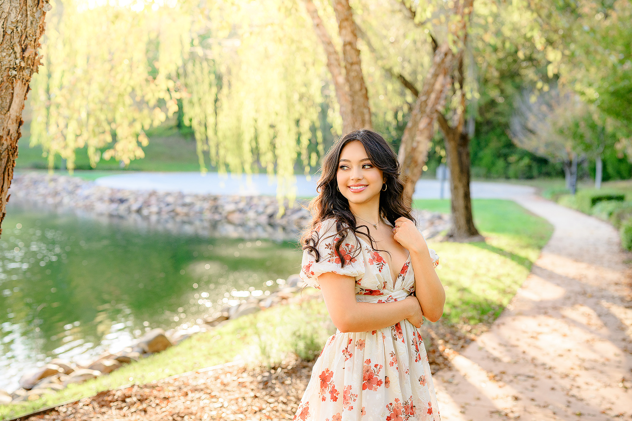 grad standing in a white dress with red flowers casually With a gorgeous smirk on her face