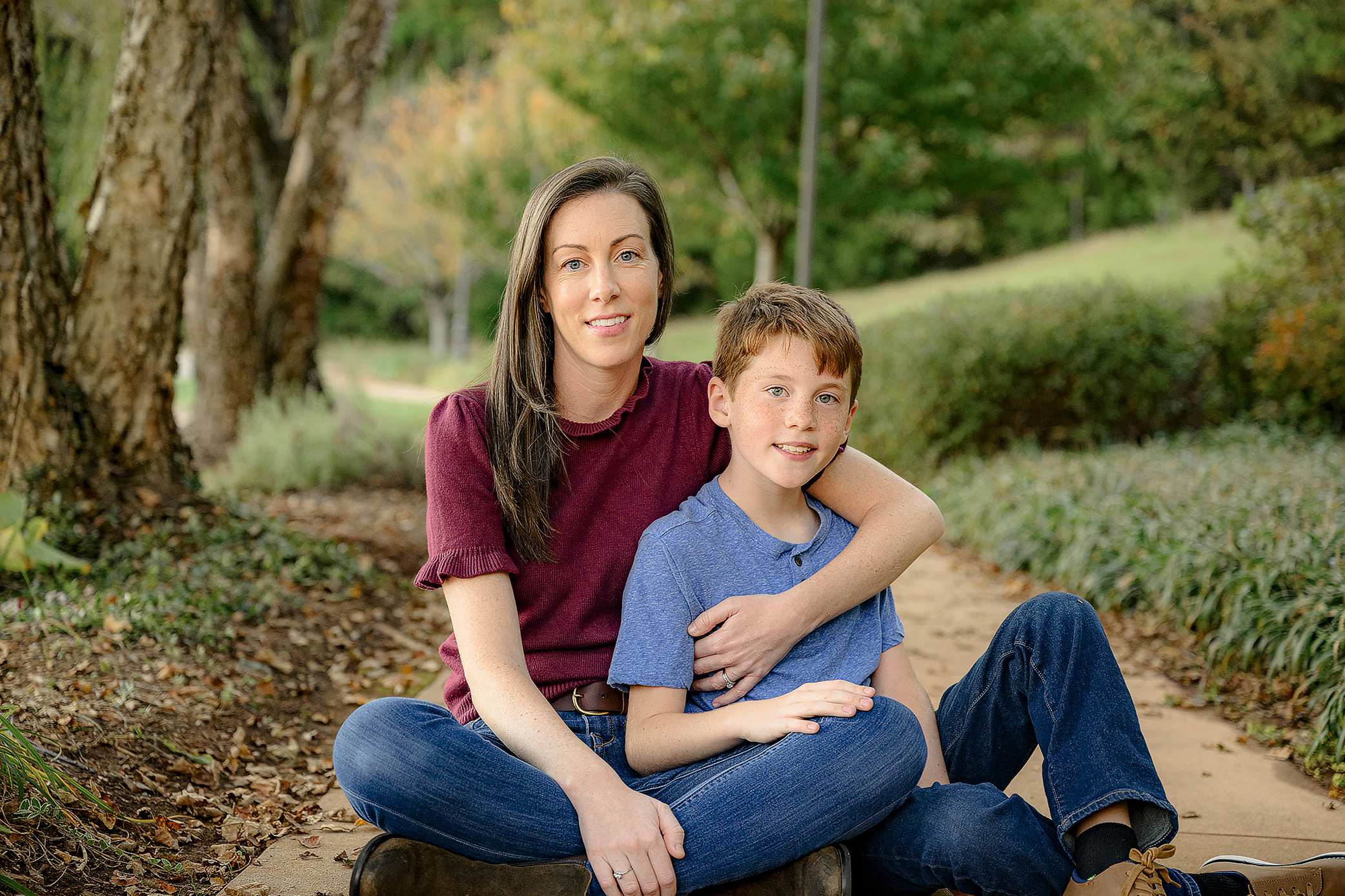 mom in burgundy sweater sits with son in blue shirt