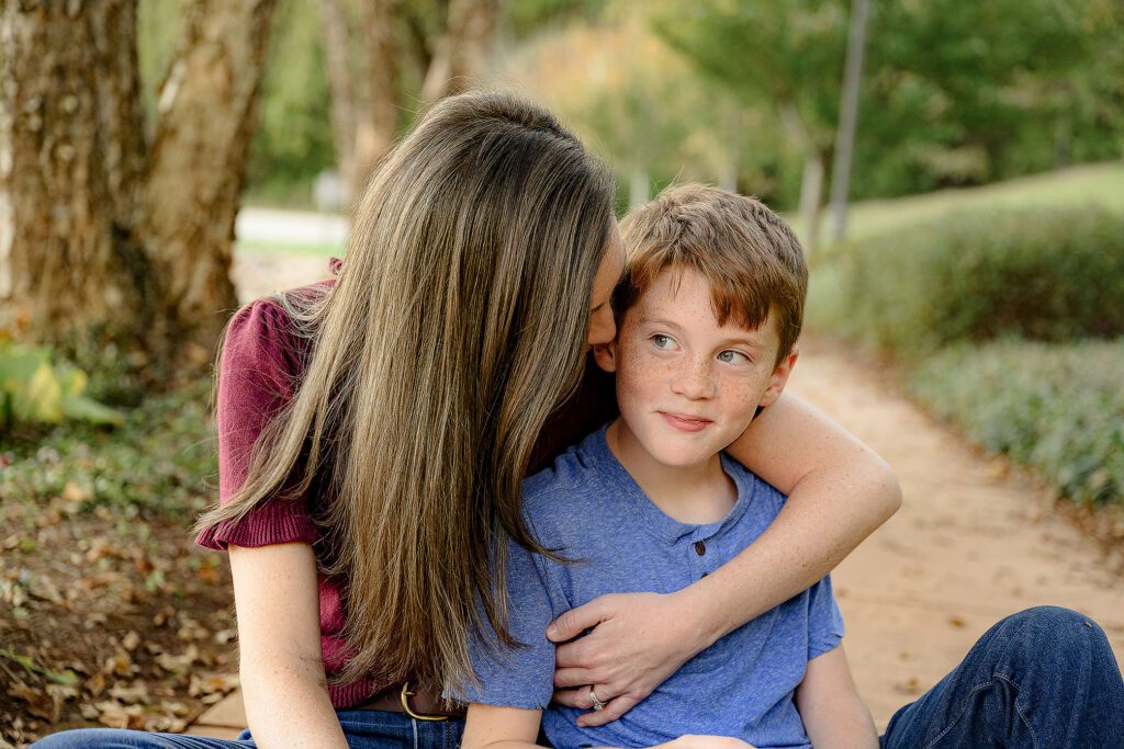 mom whispers in ear of twin son dressed in blue