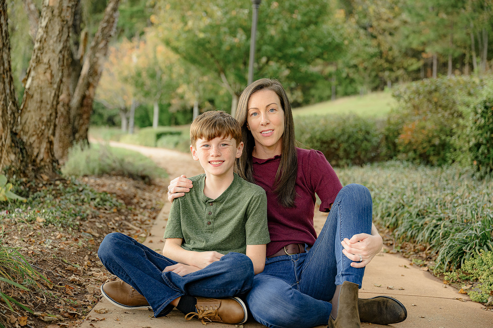 mom in burgundy sweater sits with son in blue shirt