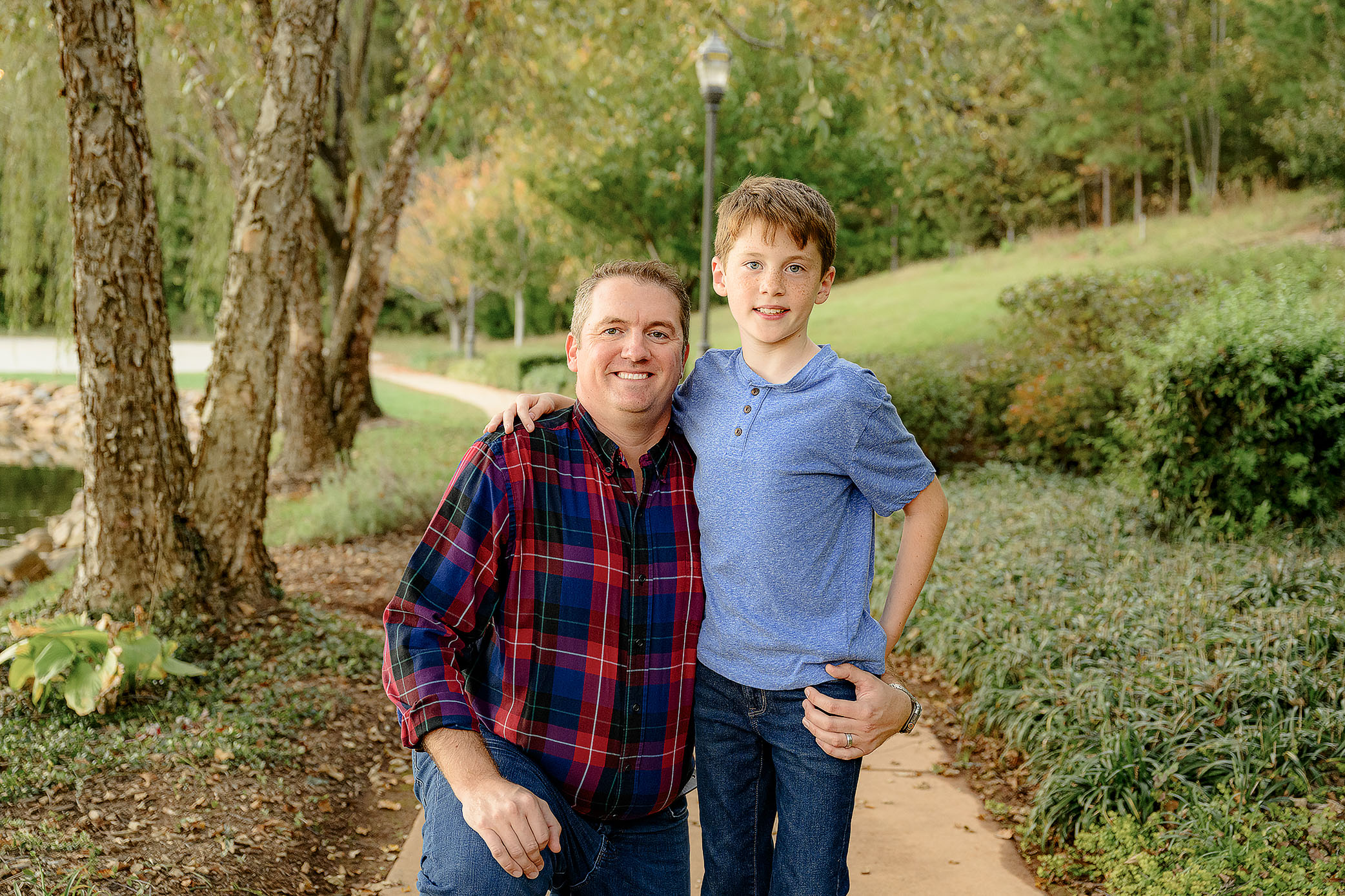 dad dressed in plaid kneeling with son dressed in blue shirt