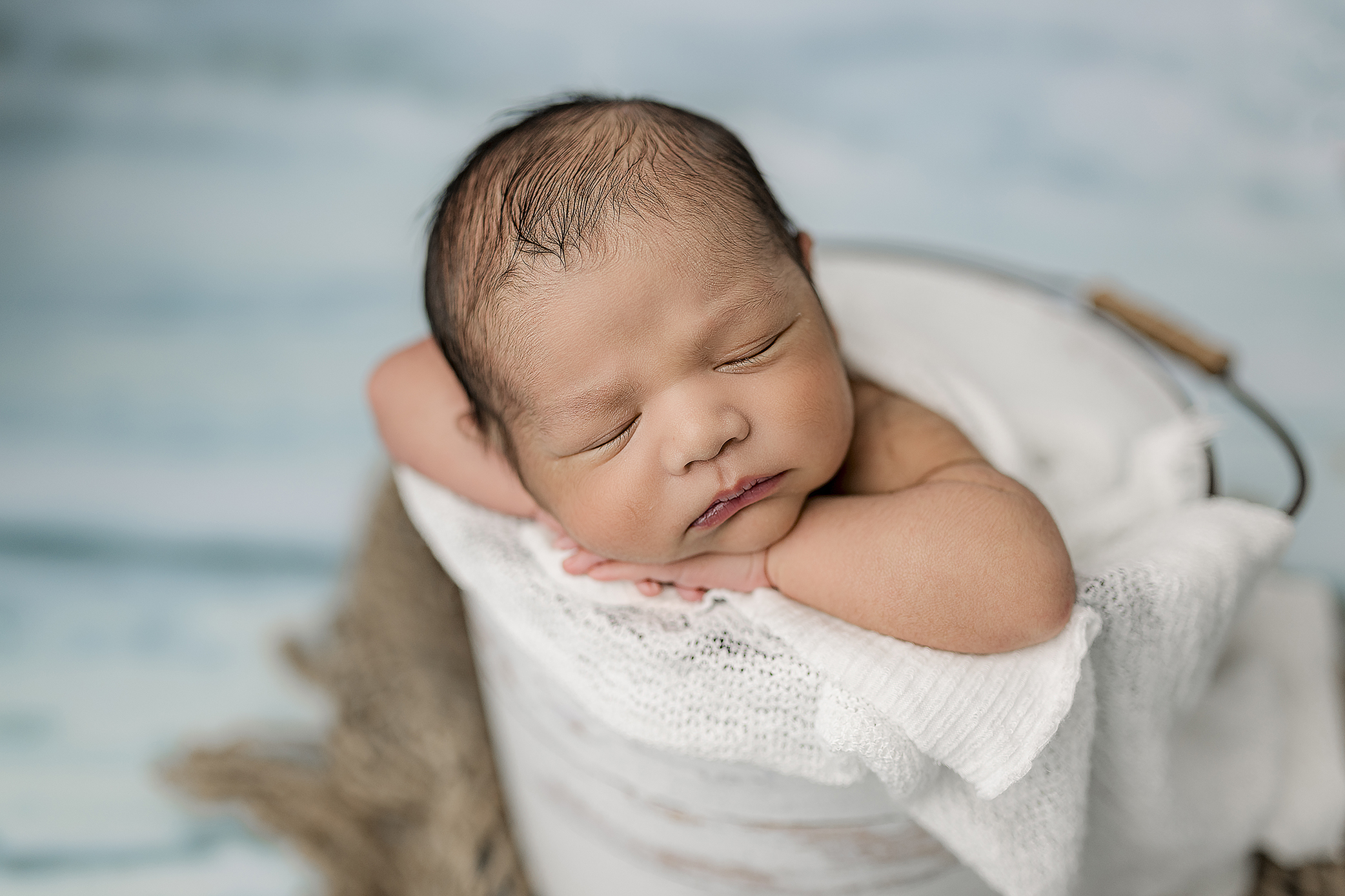 Newborn baby poses in bucket for newborn sale launch