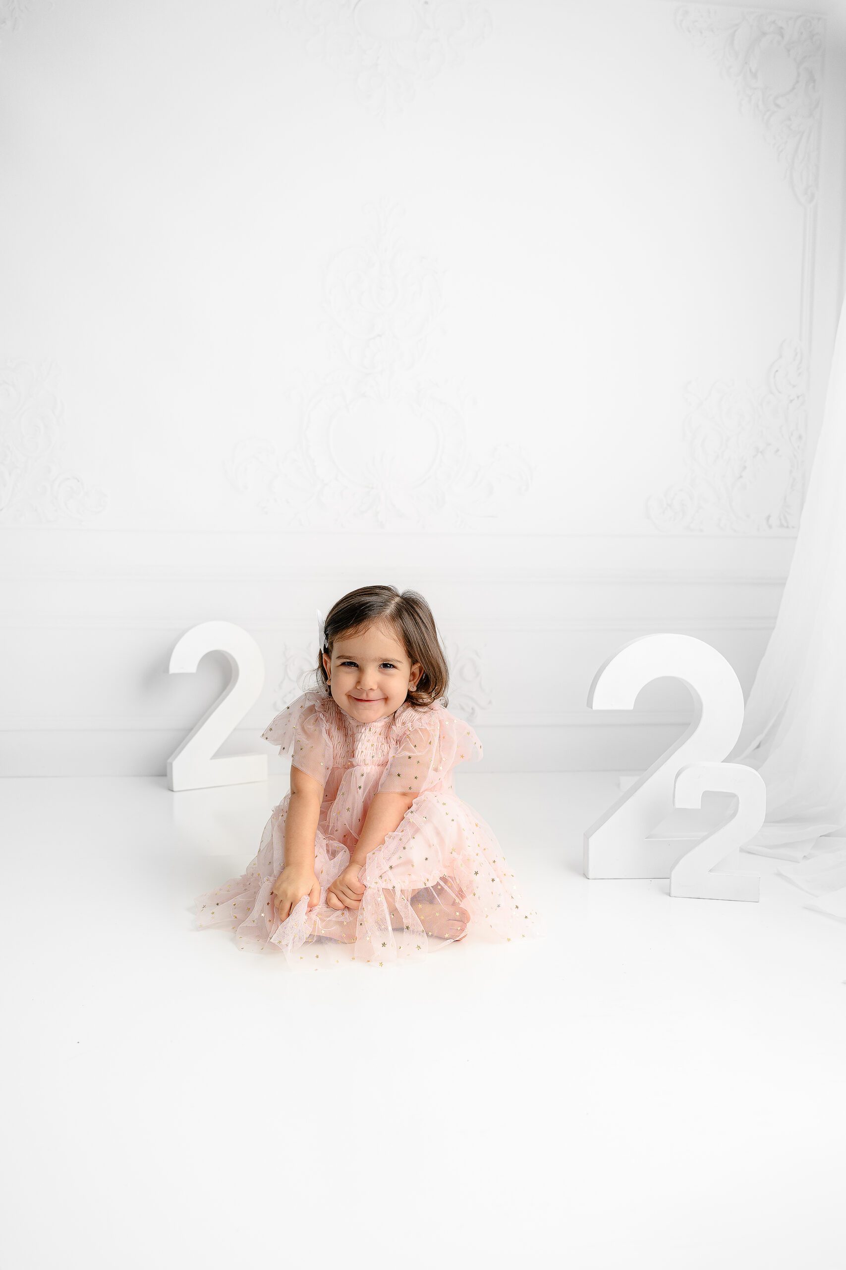 Little girl giggling while wearing a pink tulle dress with gold accents in the charlotte nc area studio