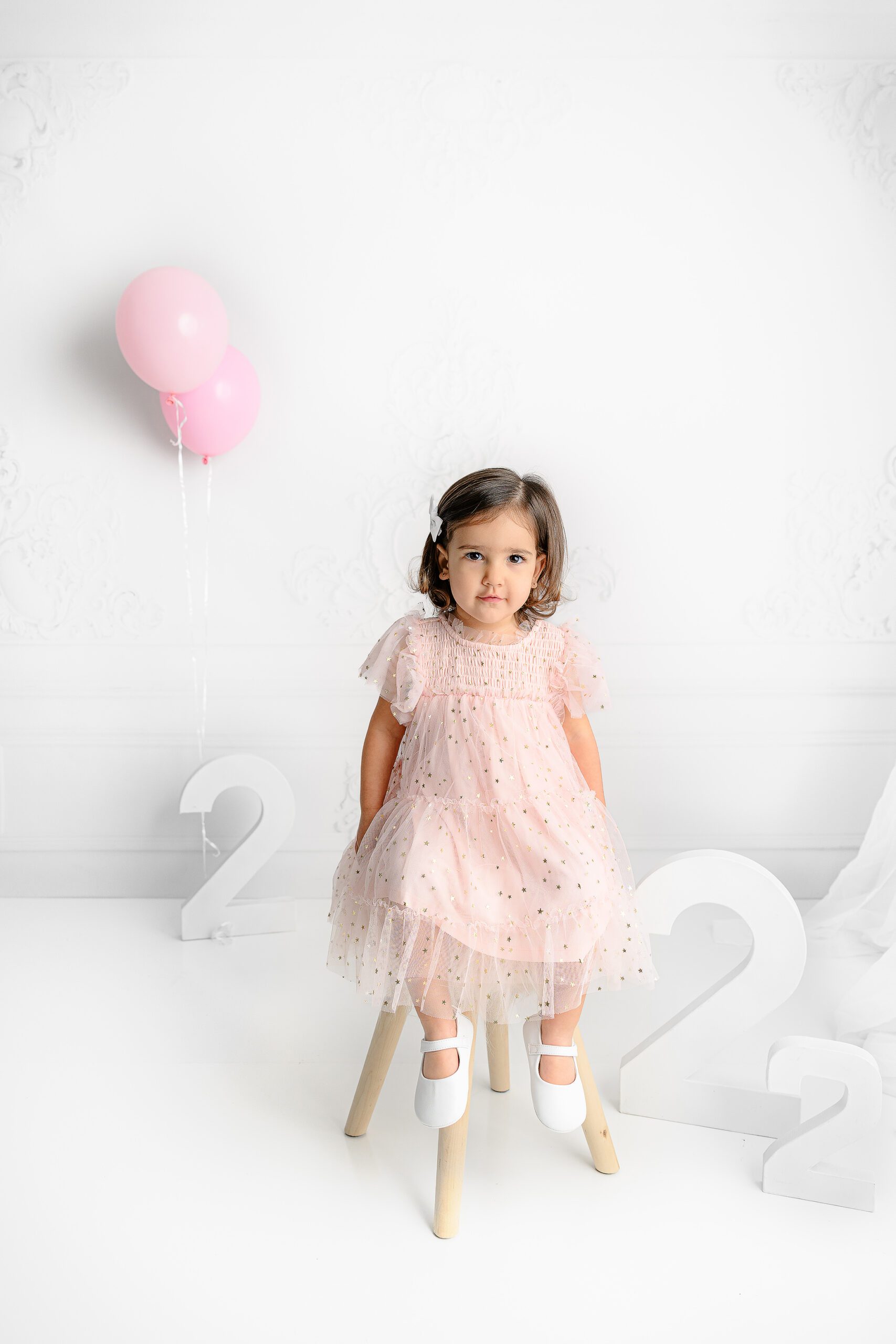 Little girl sitting on a pink stool wearing a pink tulle dress the gold accents in the waxhaw, nc studio
