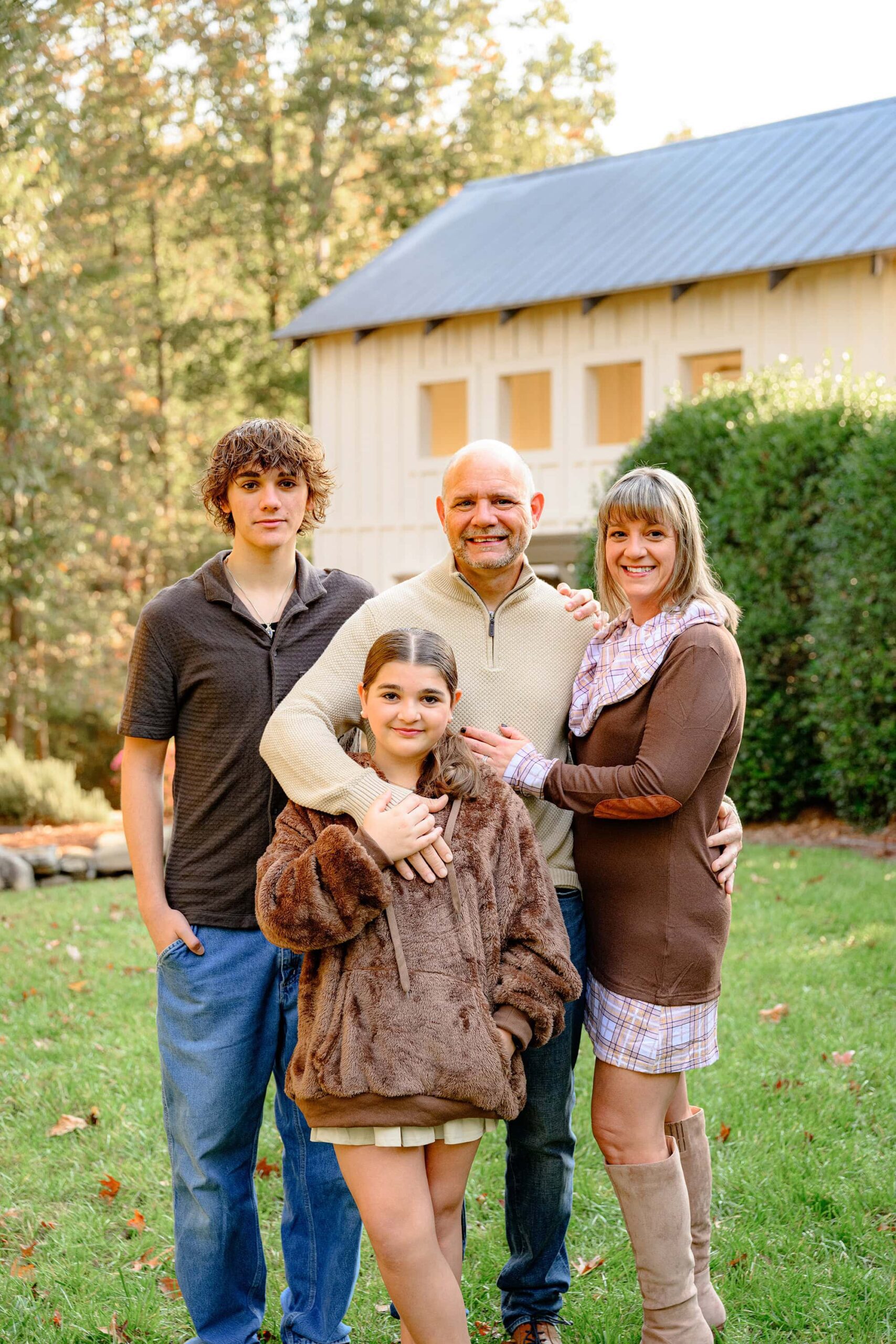 family of four dressed in brown tones standing together during their oldest sons senior photo session