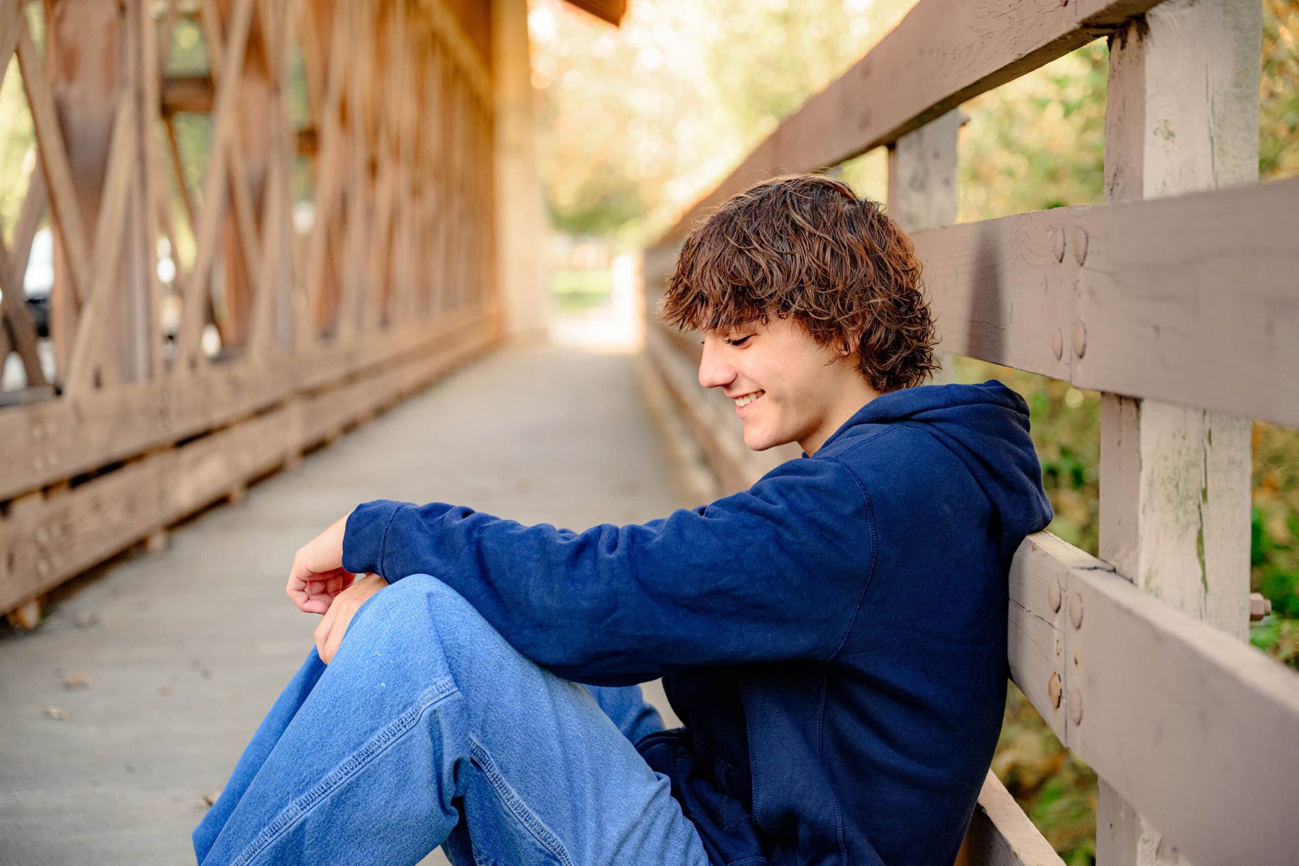 surrounded by beautiful fall golden light this class of 2025 grad takes a moment to laugh and relax during his session