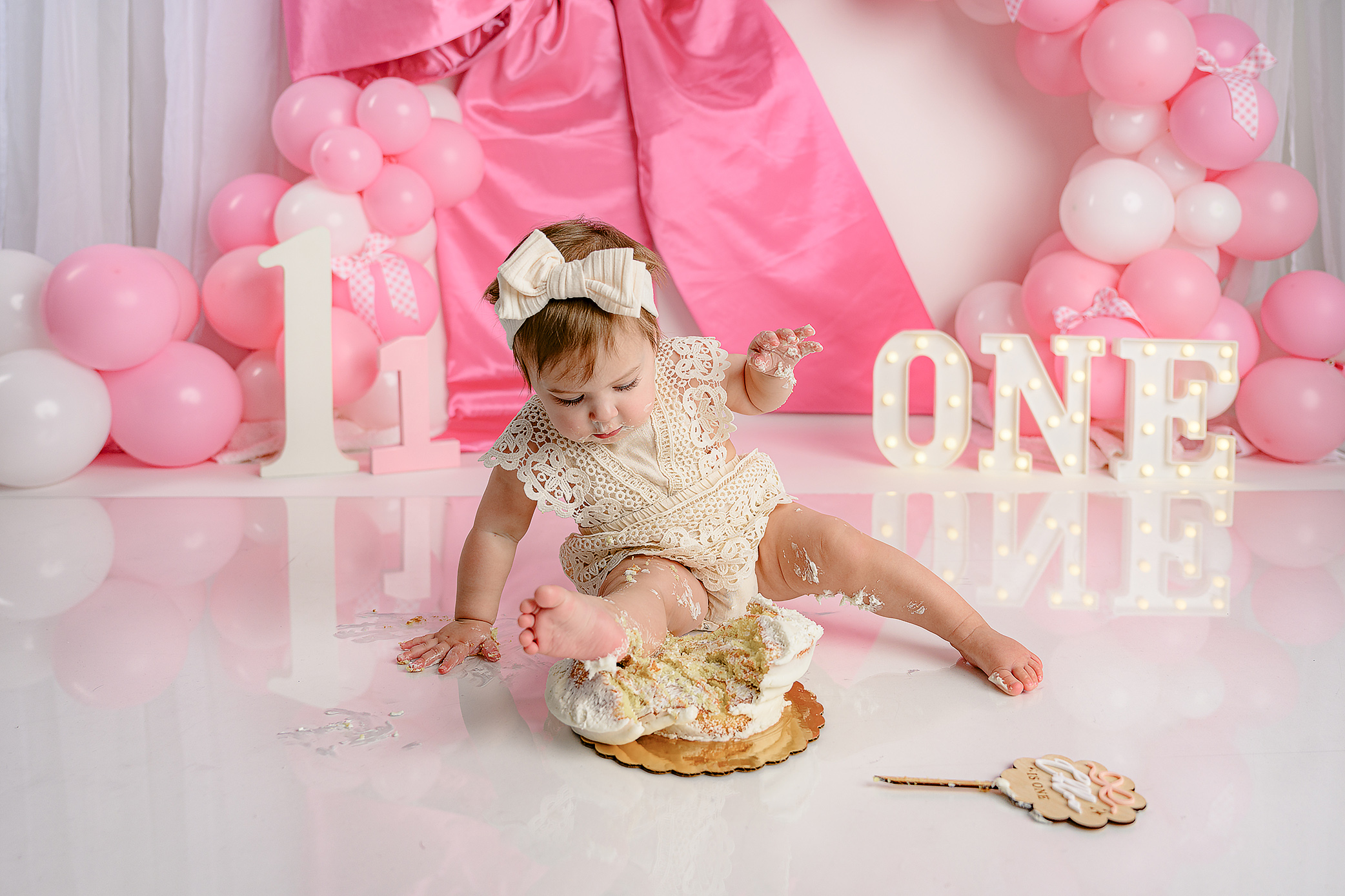Fun reaction from a little girl as her leg is in her smash cake during her milestone one-ear-old photo session