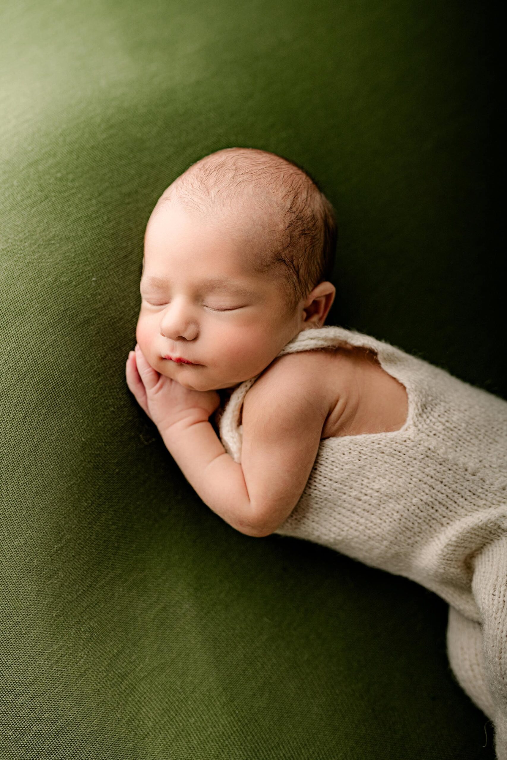 Charlotte area newborn boy lays on his side during his newborn photography session with his hands posed gently under his cheek