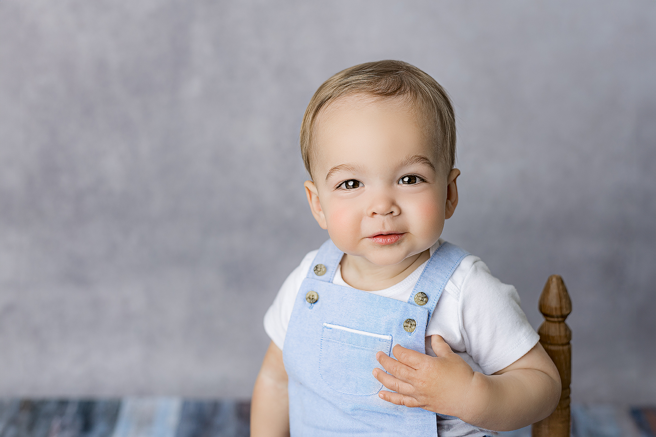 one year old milestone session in waxhaw nc studio with boy dressed in white shirt and blue overalls