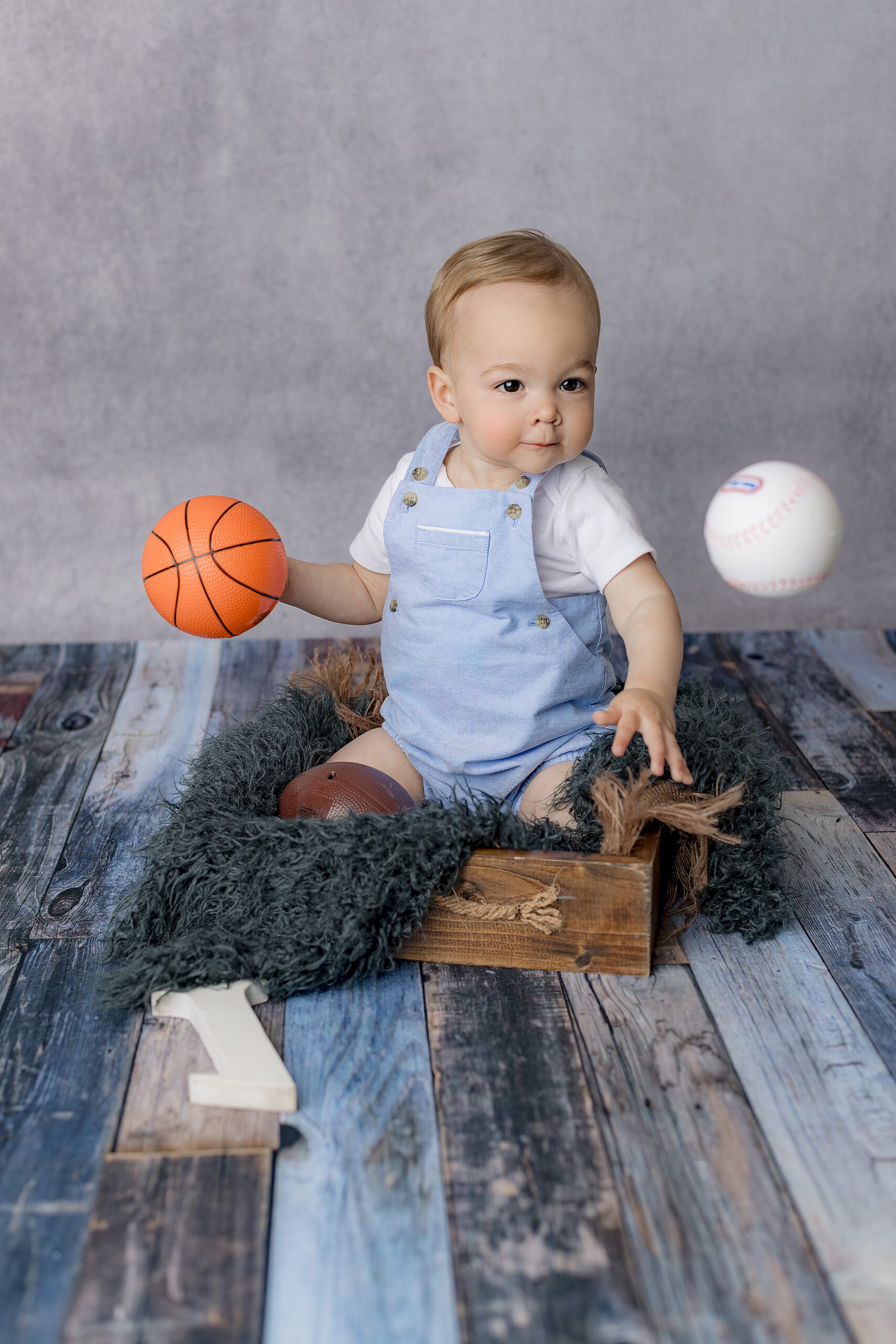 staring intensely little boy thows his balls he brought from home during his milestone session to celebrate his birthday