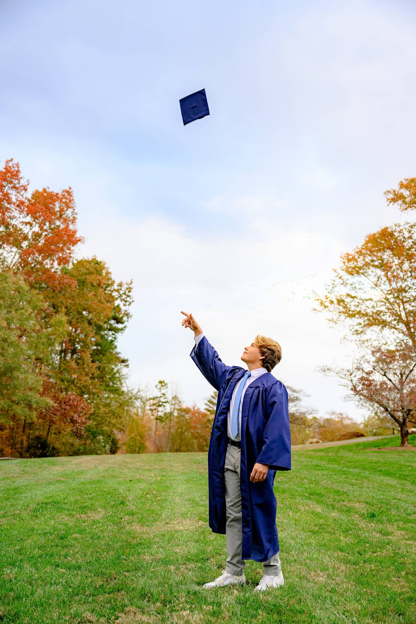 Union County North Carolina CHS class of 2025 grad tosses his cap during his senior portrait session in a waxhaw park