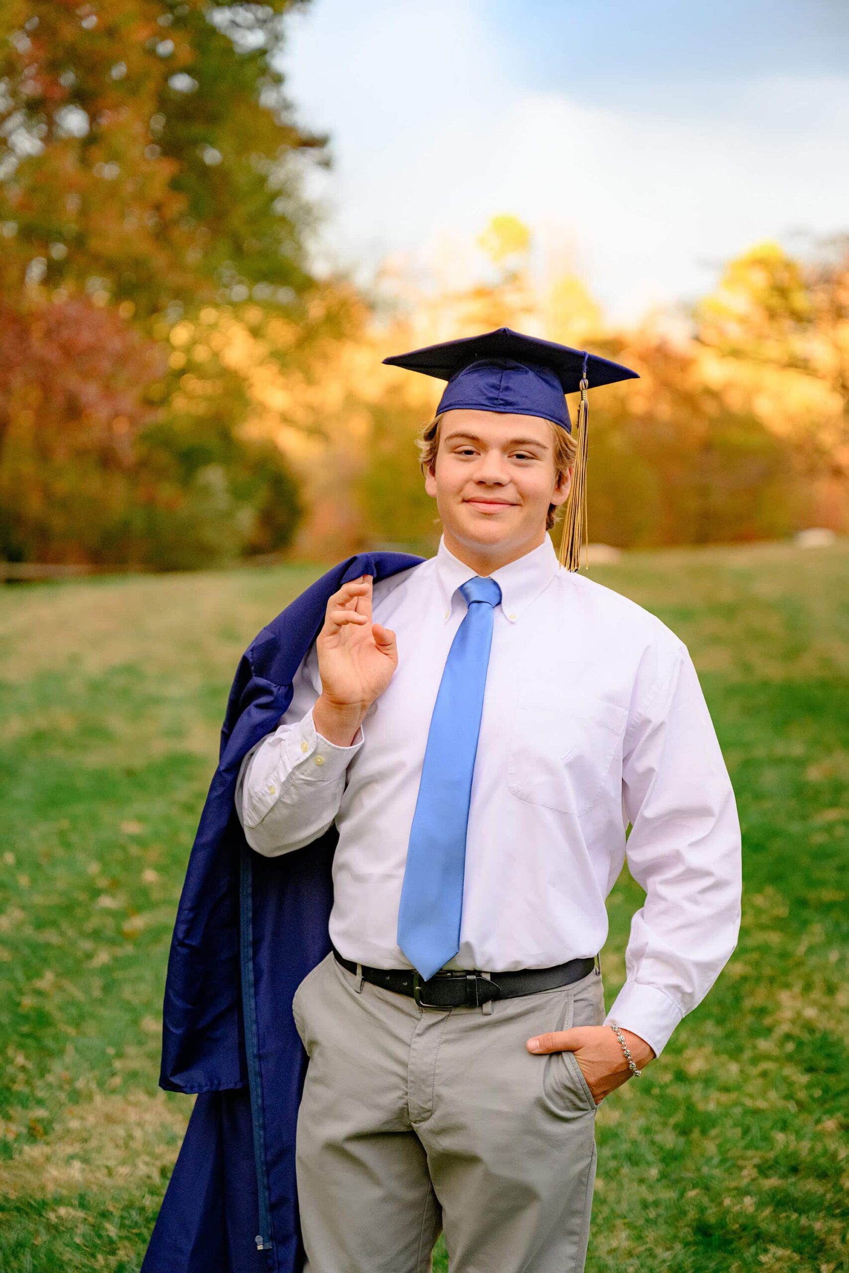 Wearing his cap and tassel this union county grad stands in his formal white shirt, tie, and pants holding his grad gown