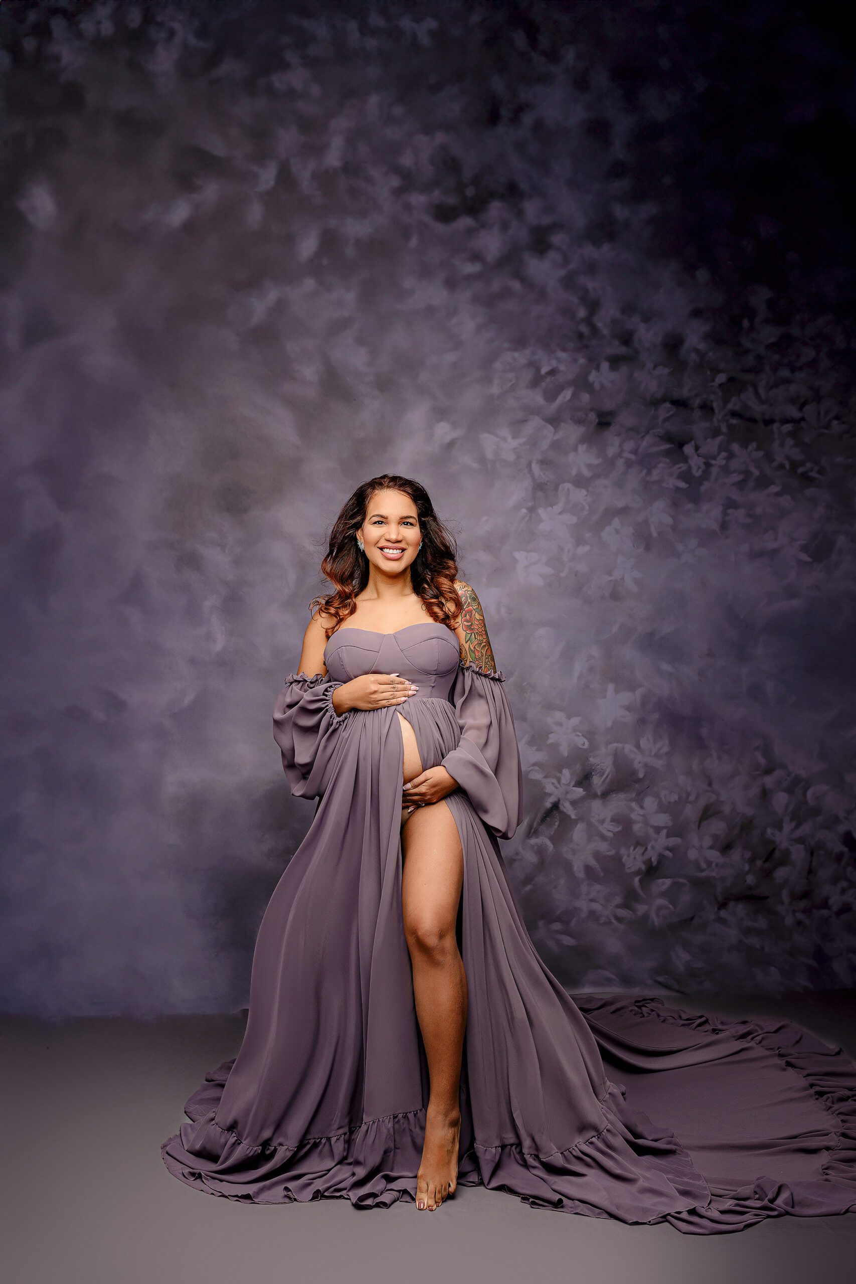 with her hands on her belly both top and bottom a mom-to-be smiles toward the camera while posing during her waxhaw, nc studio session