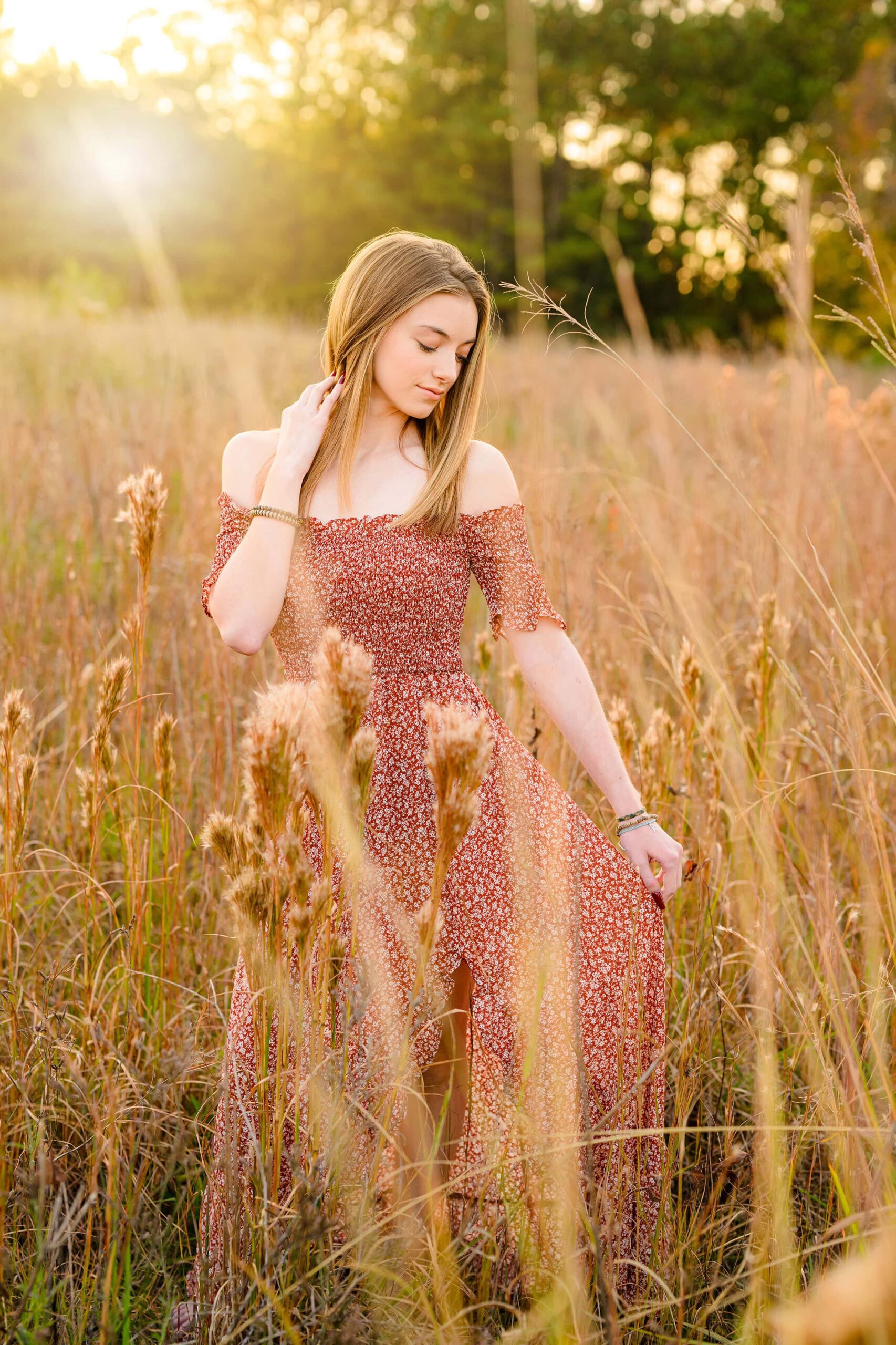 sun glow is shining down on senior girl while she holds her dress in a charlotte nc area field