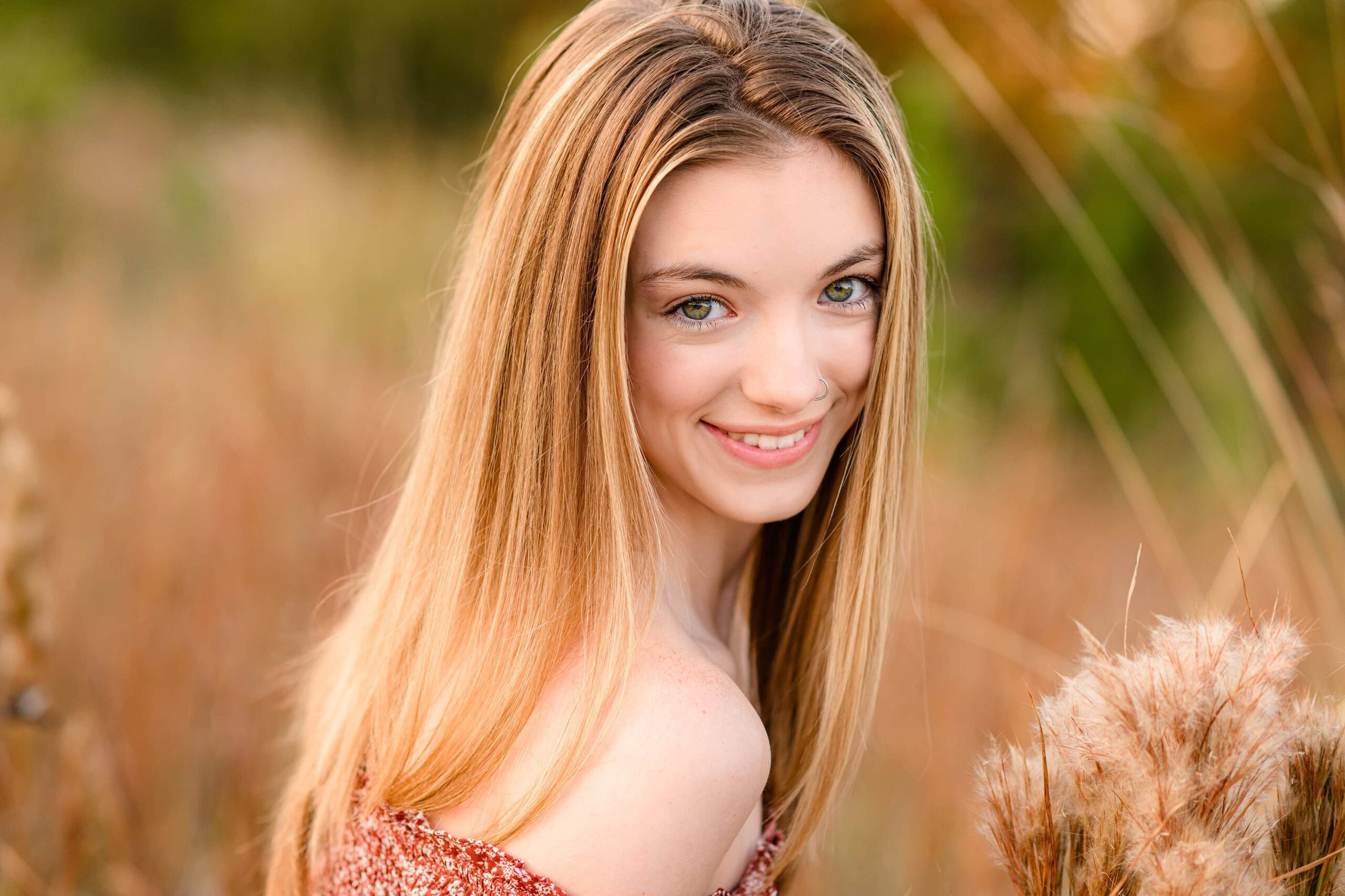 hazel eyes on this senior steal the show as she is looking over her shoulder smiling surrounded by winter field grasses in the charlotte area