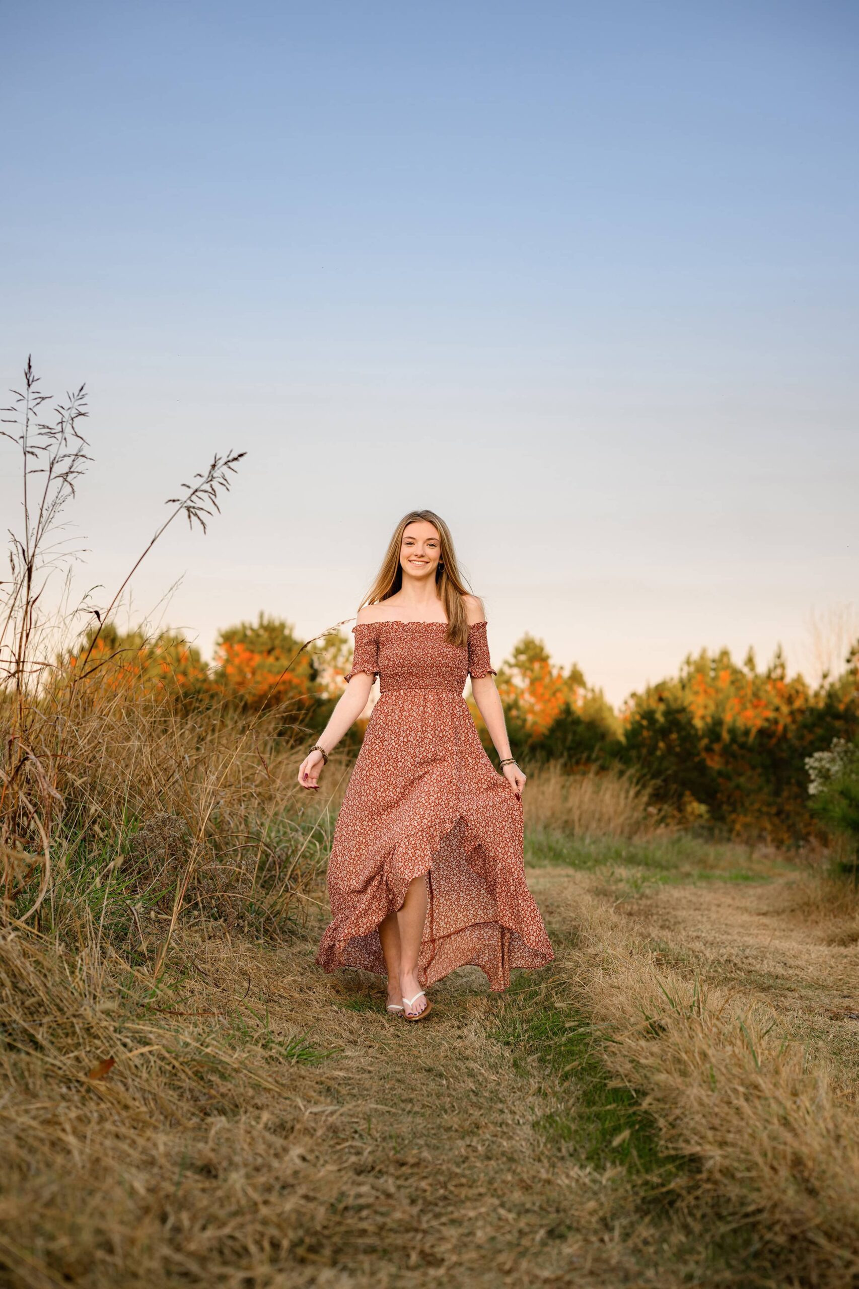 senior girls dress falls back as she walks with her wind in her hair
