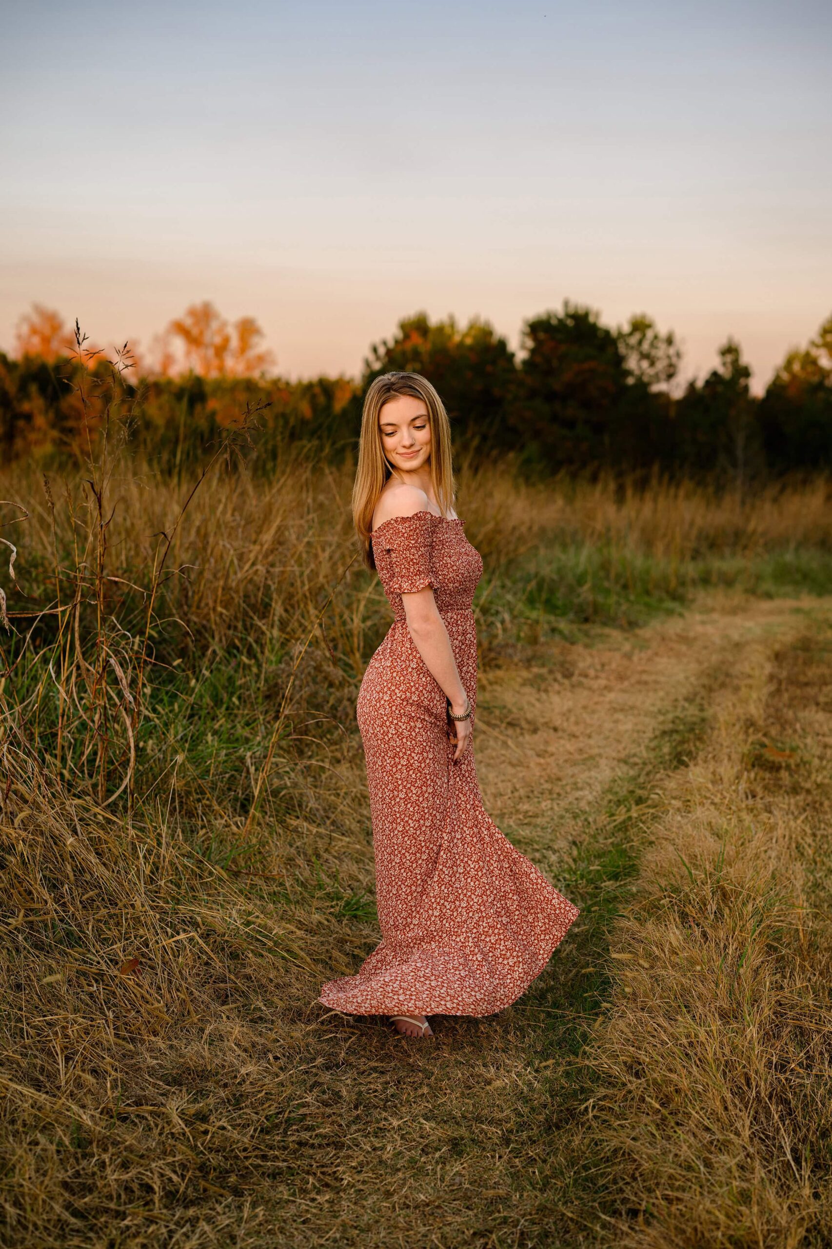 senior girl twirls in a field with a rust colored dress