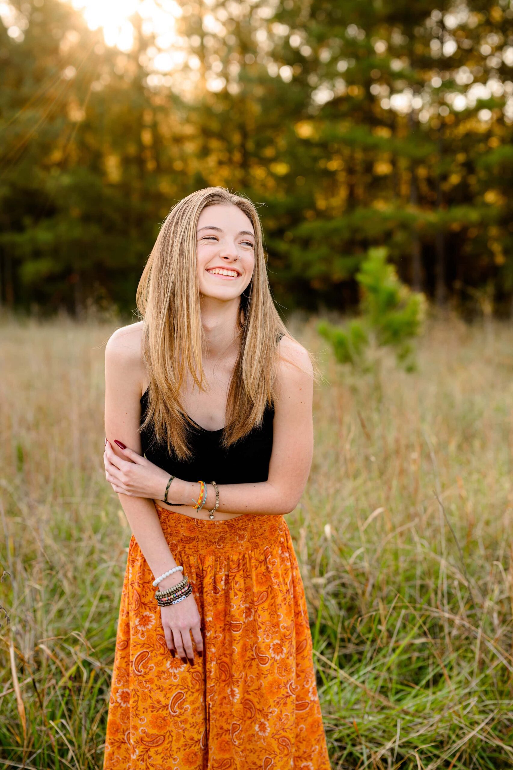 senior girl laughs as she poses during her grad photos