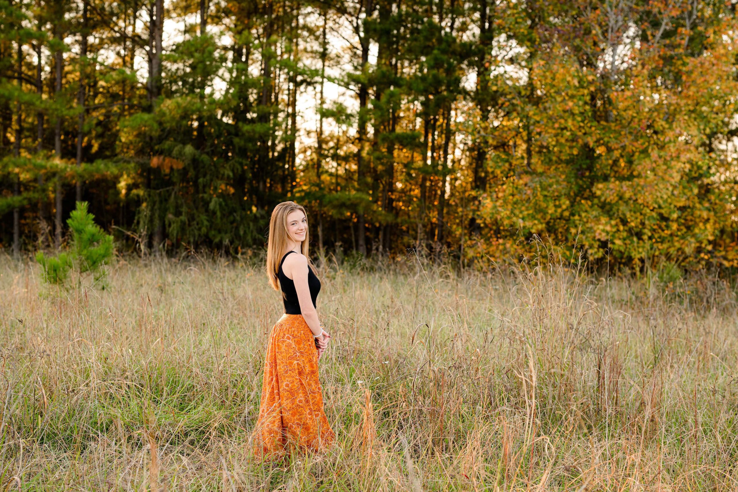 black crop top and orange skirt pop on this grad in this open fall field in waxhaw