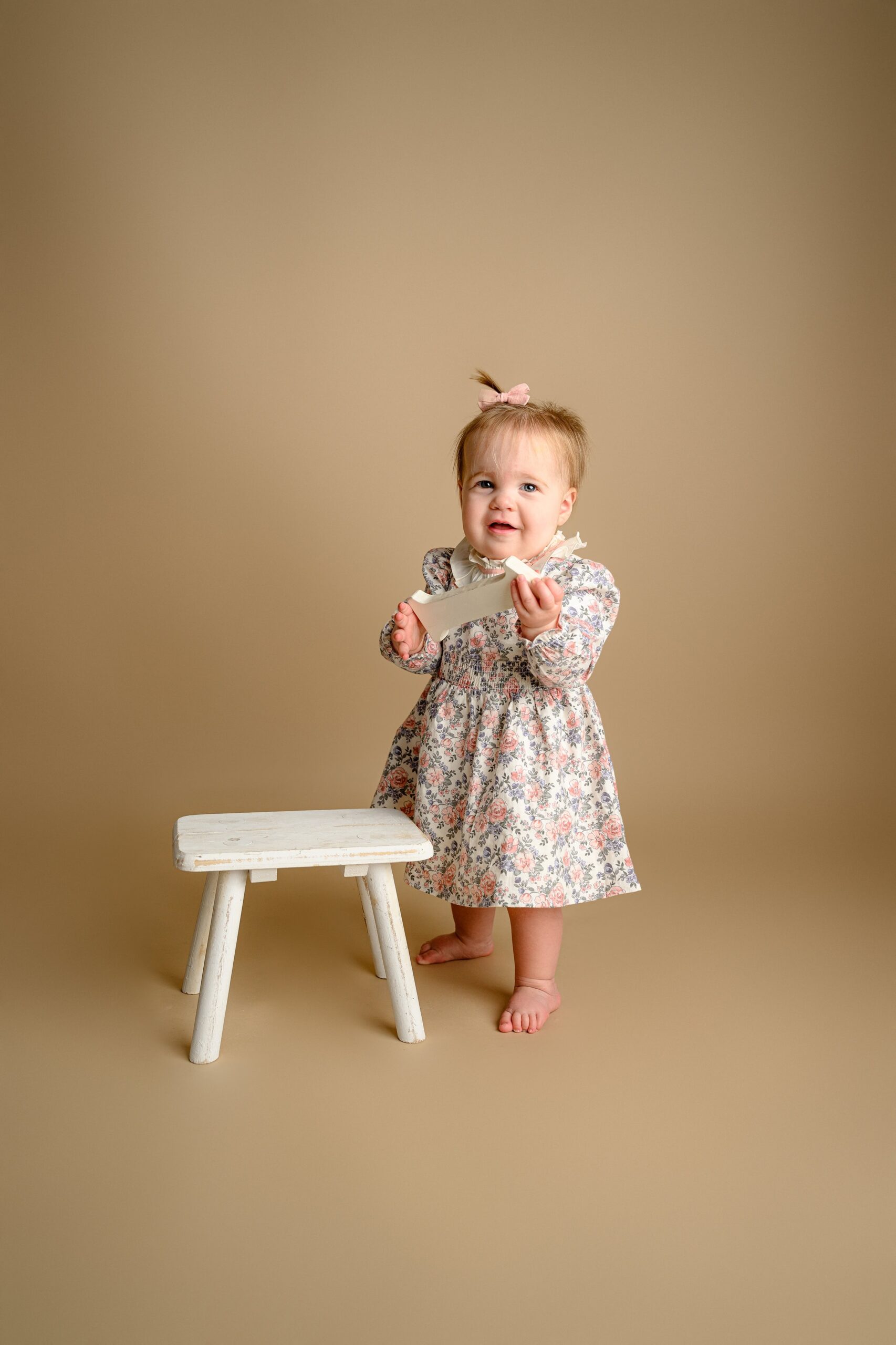 holding a number one prop this little girl stands proudly for the first time during her milestone photos