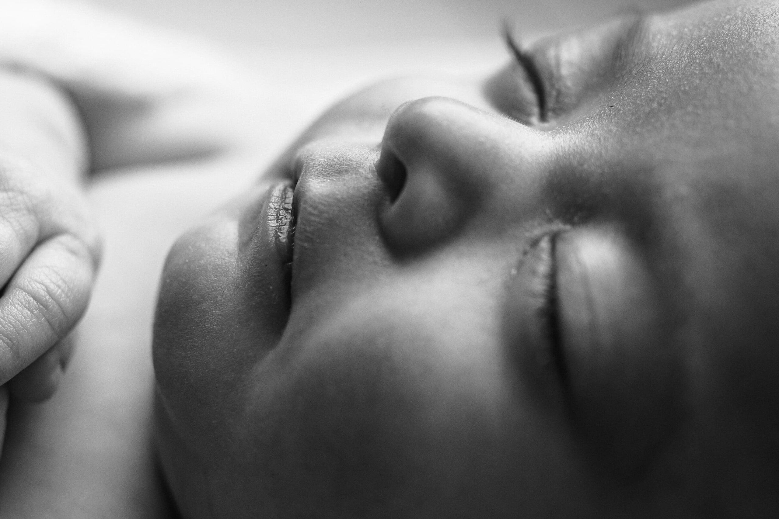 A tender black and white image capturing the newborn’s tiny nose and lips.