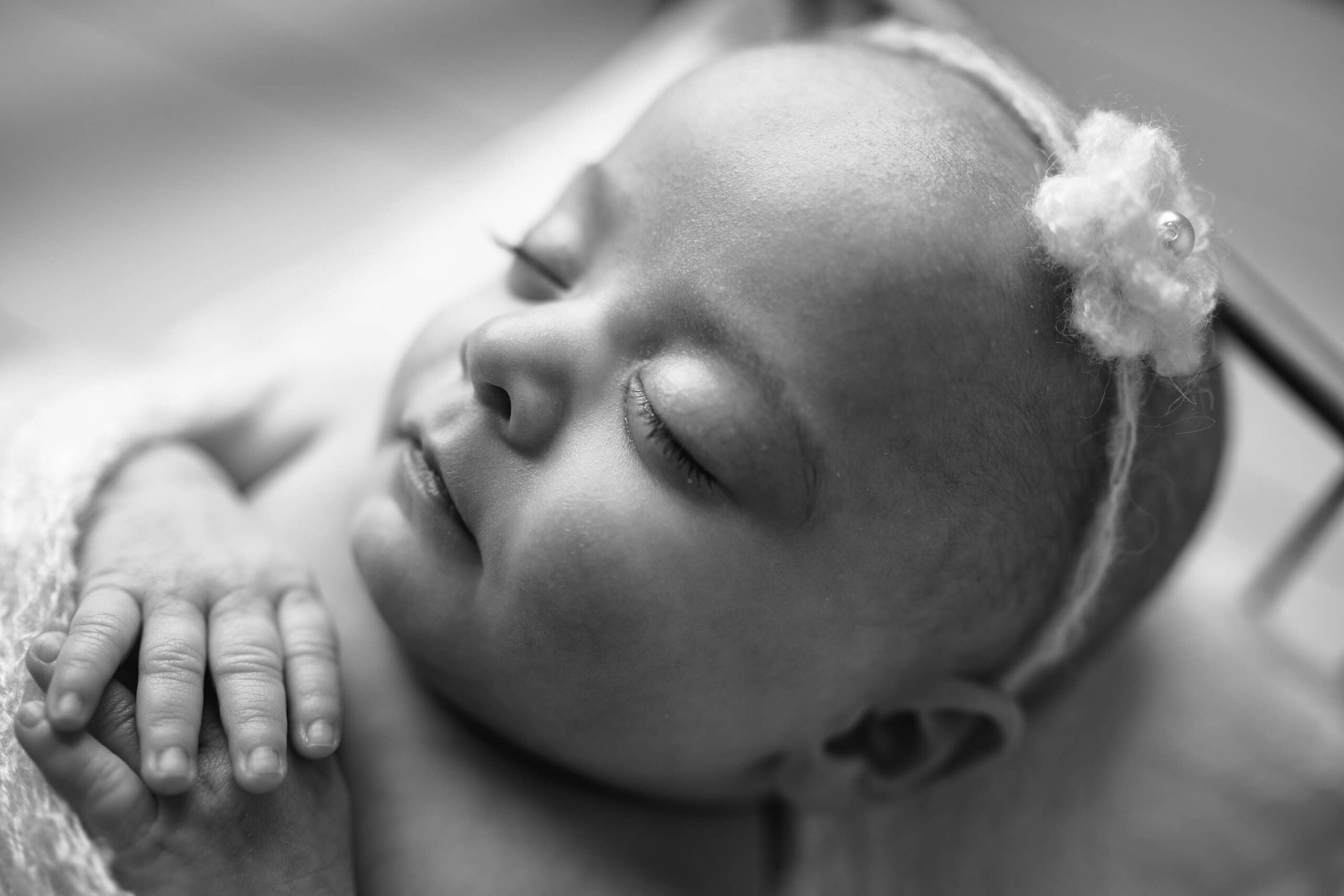 Black and white portrait of a newborn girl’s delicate side profile, taken in a Waxhaw, NC studio.