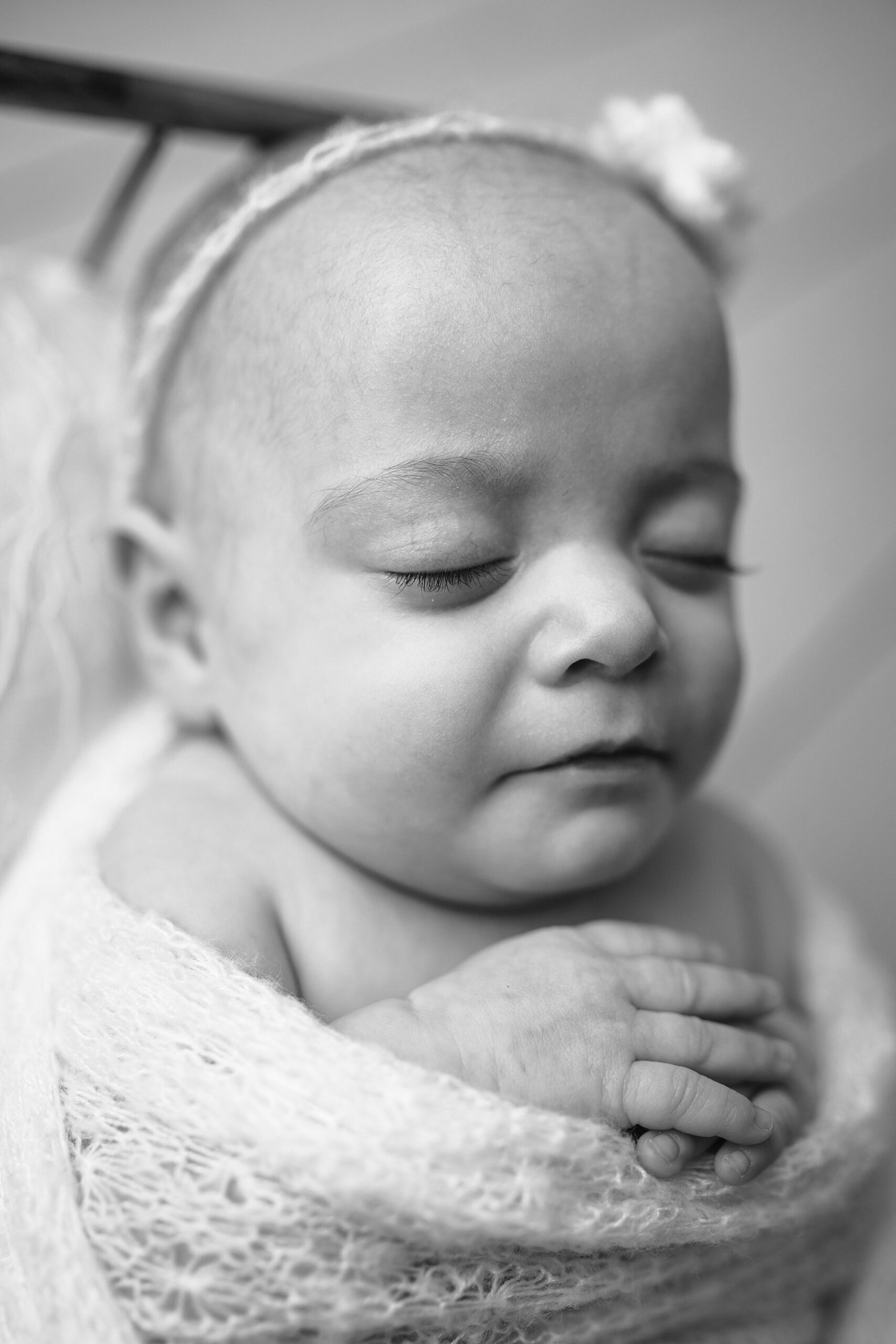 Striking black and white side profile of a studio session with a newborn girl, softly lit to highlight her delicate features.