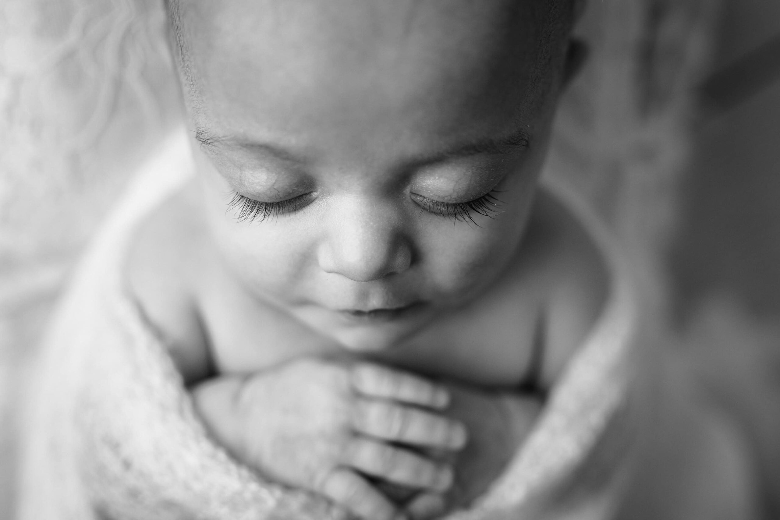 Detailed Black and white overhead photo showcasing the Waxhaw newborn’s long, delicate eyelashes.