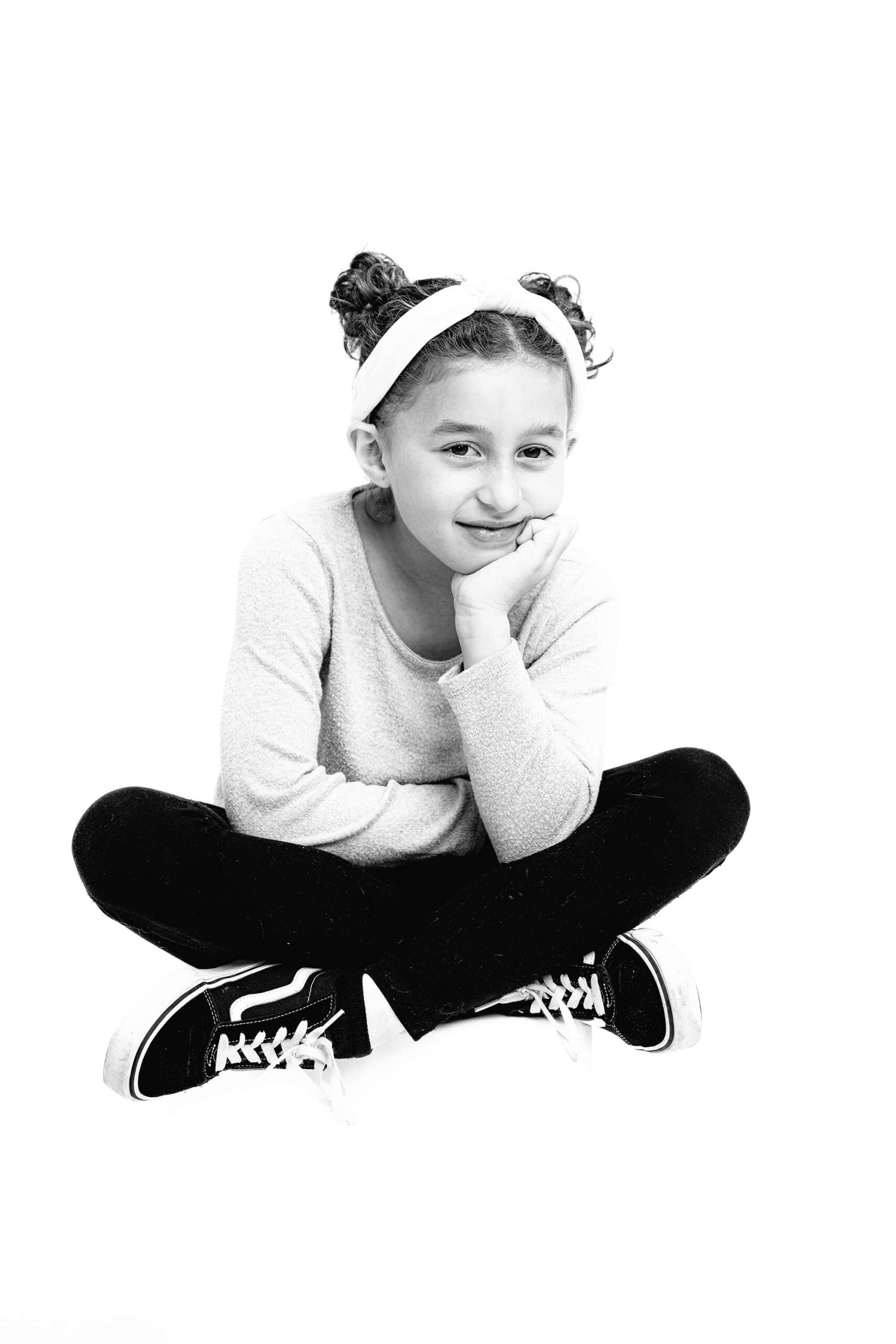 black and white girl sitting crossed legged on a stool with her hand by her cheek