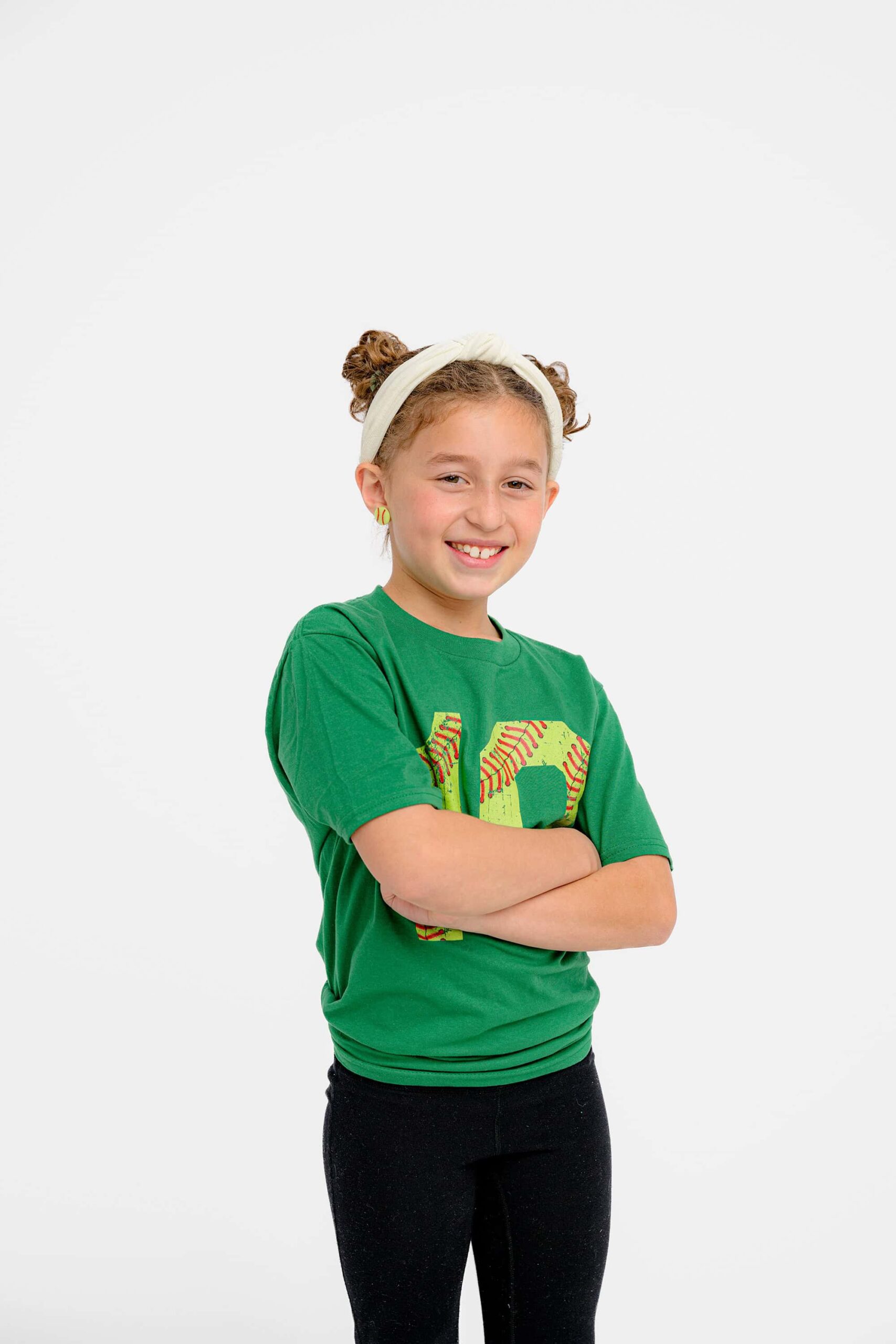 girl stands with her arms crossed laughing while wearing a green shirt and pants