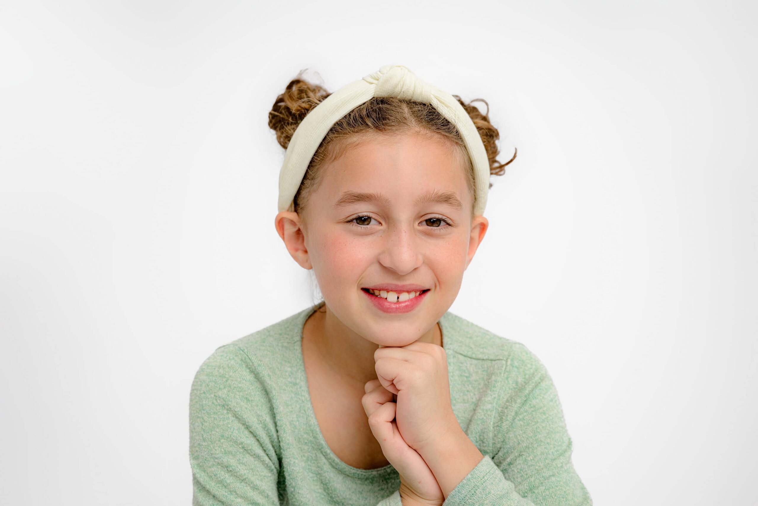 close up image of a ten year old girl wearing a headband and a green shirt