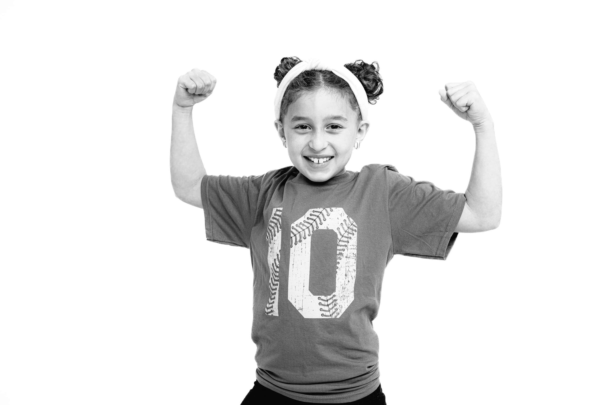 black and white image of girl posing with two arms up wearing a number 10 shirt