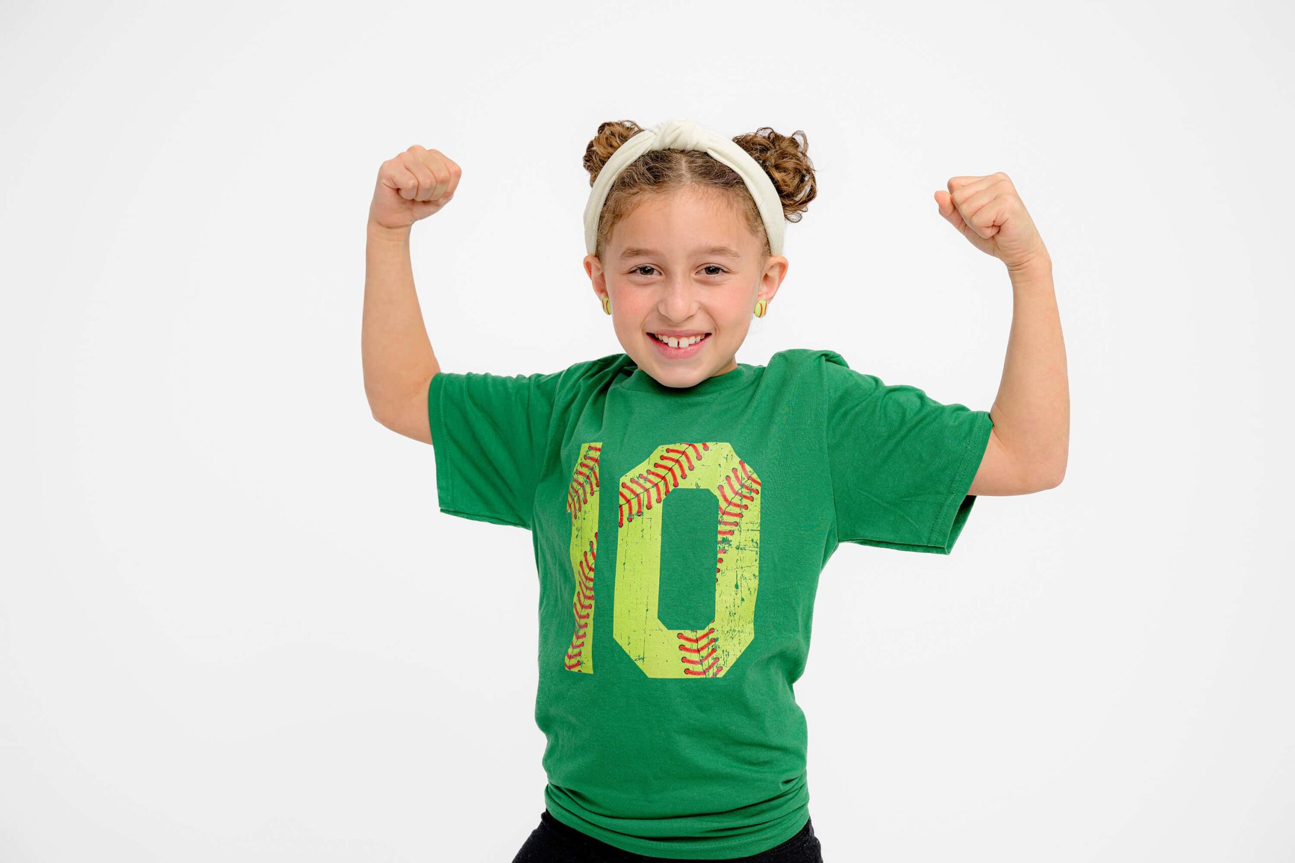 ten year old girl celebrates her milestone 10th birthday wearing a green shirt and the number 10 posing showing her muscles