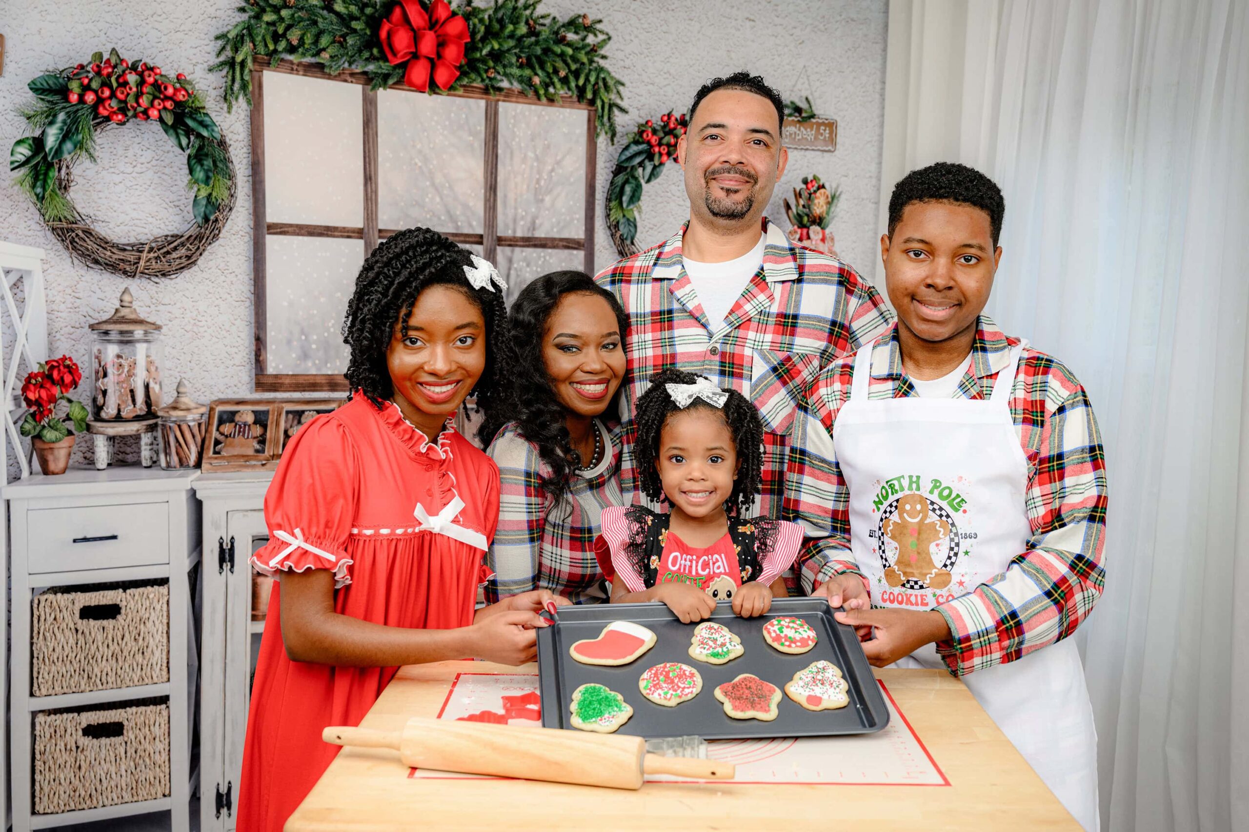 A Charlotte area family is dressed festively for their holiday inspired studio session, holding a tray of Christmas cookies