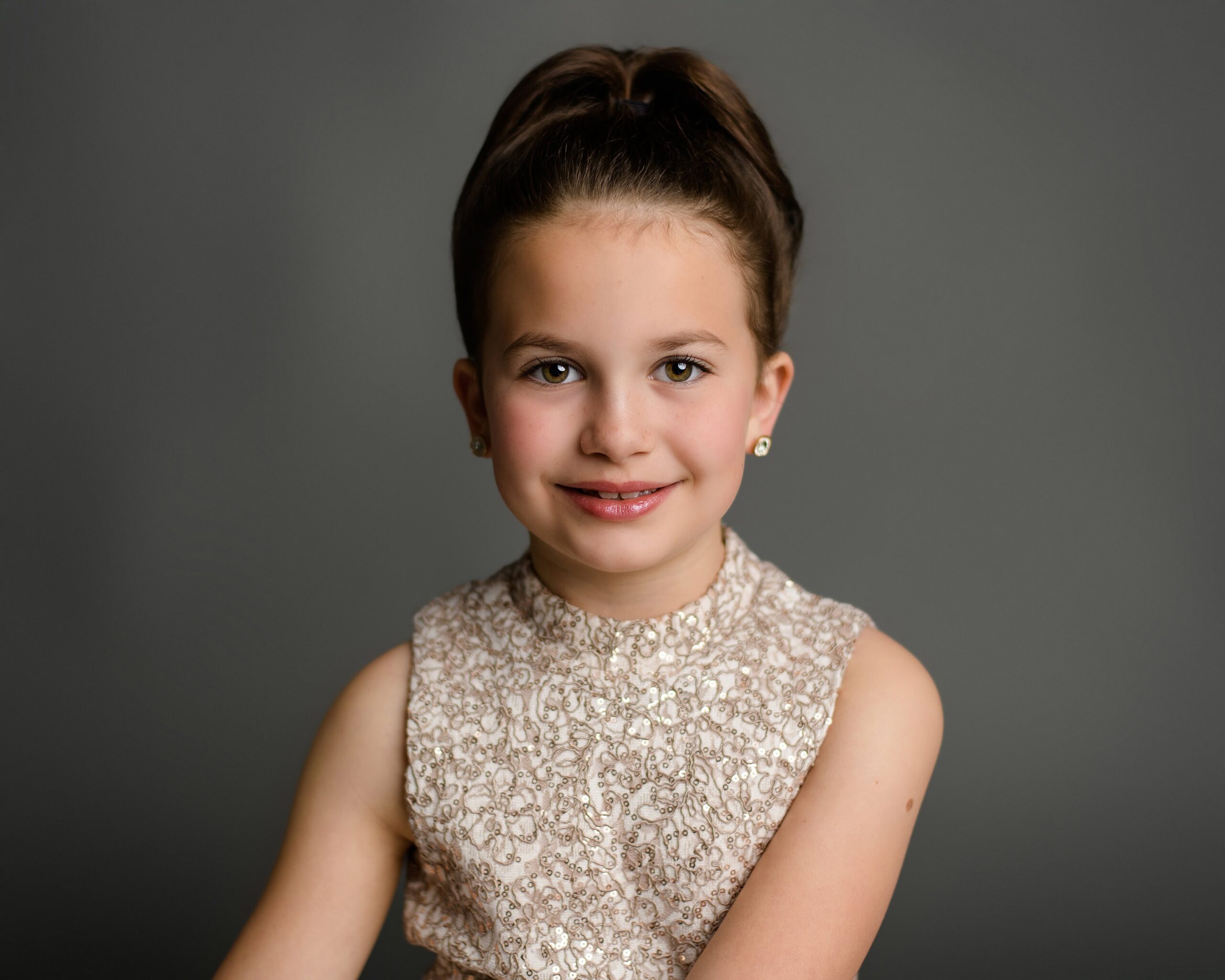 A waxhaw girl dressed in gold with her hair and Aubrey Hepburn style poses to capture a close-up image of her during her studio photography session