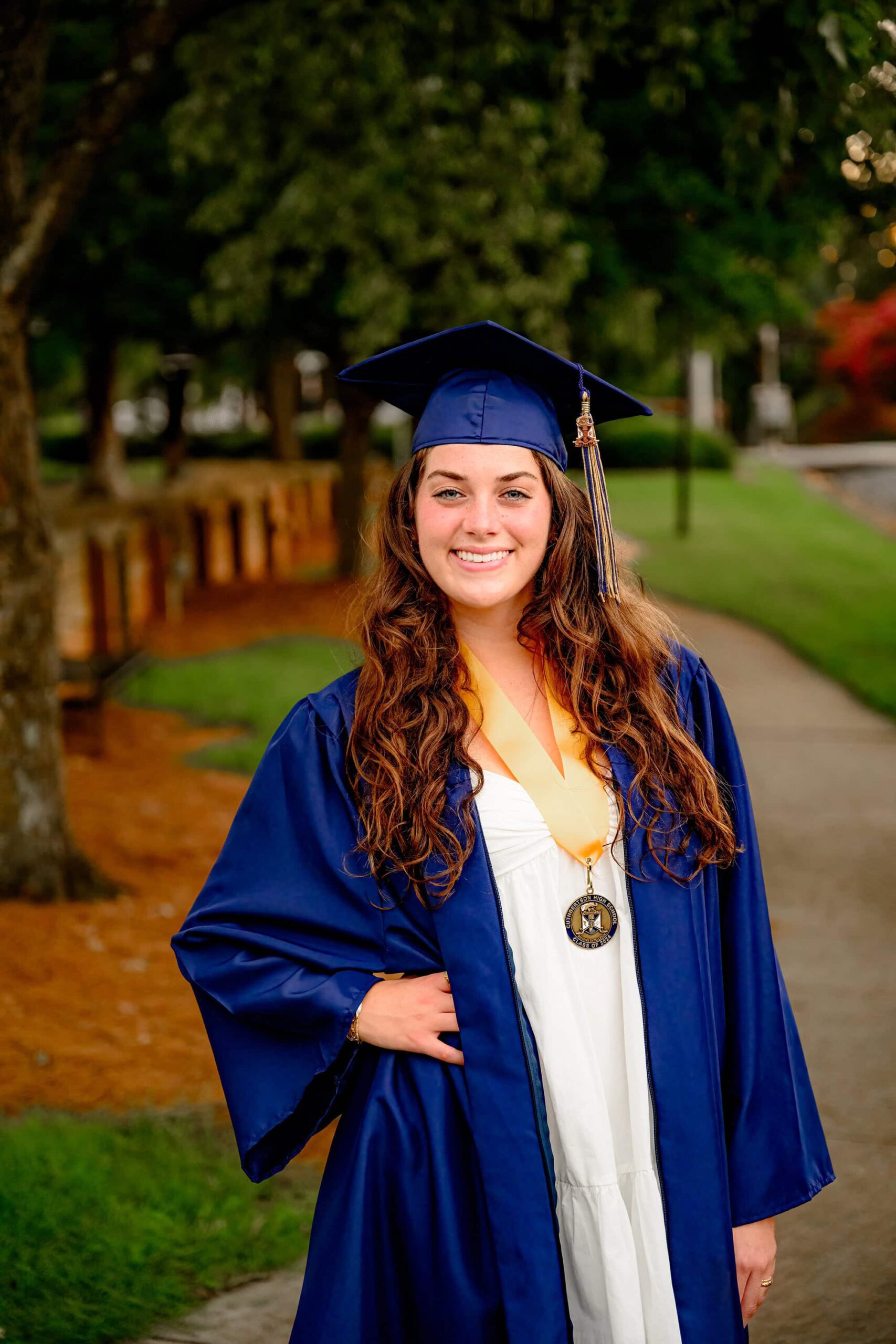 Draped in her full blue cap and gown, Emma Hines stands proudly, wearing her graduation medal as she celebrates her achievement as a Cuthbertson High School senior in downtown Waxhaw.