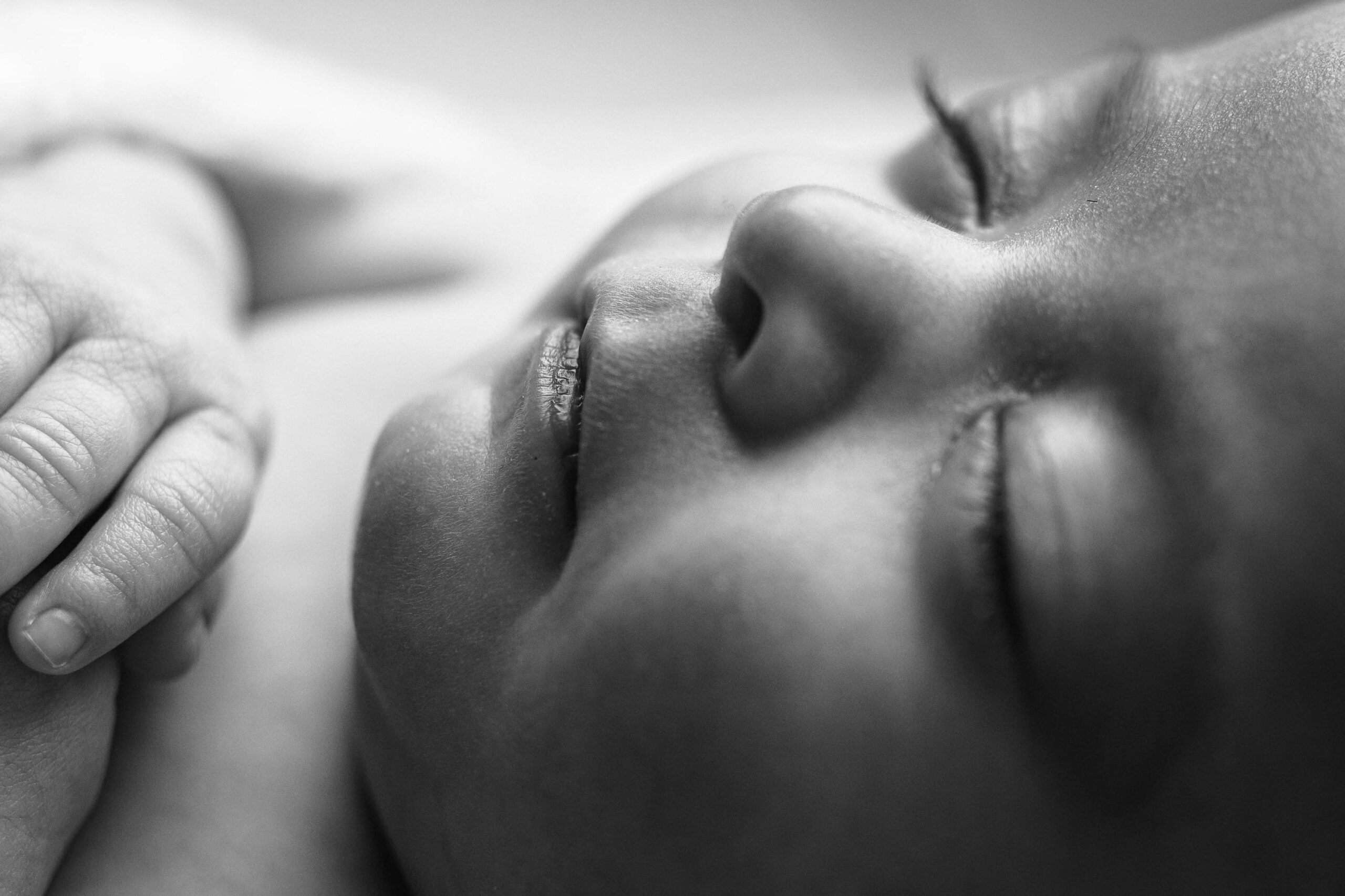 Close-up of a newborn baby's tiny lips in black and white, captured in the Charlotte studio, emphasizing the softness and sweetness of her delicate features.