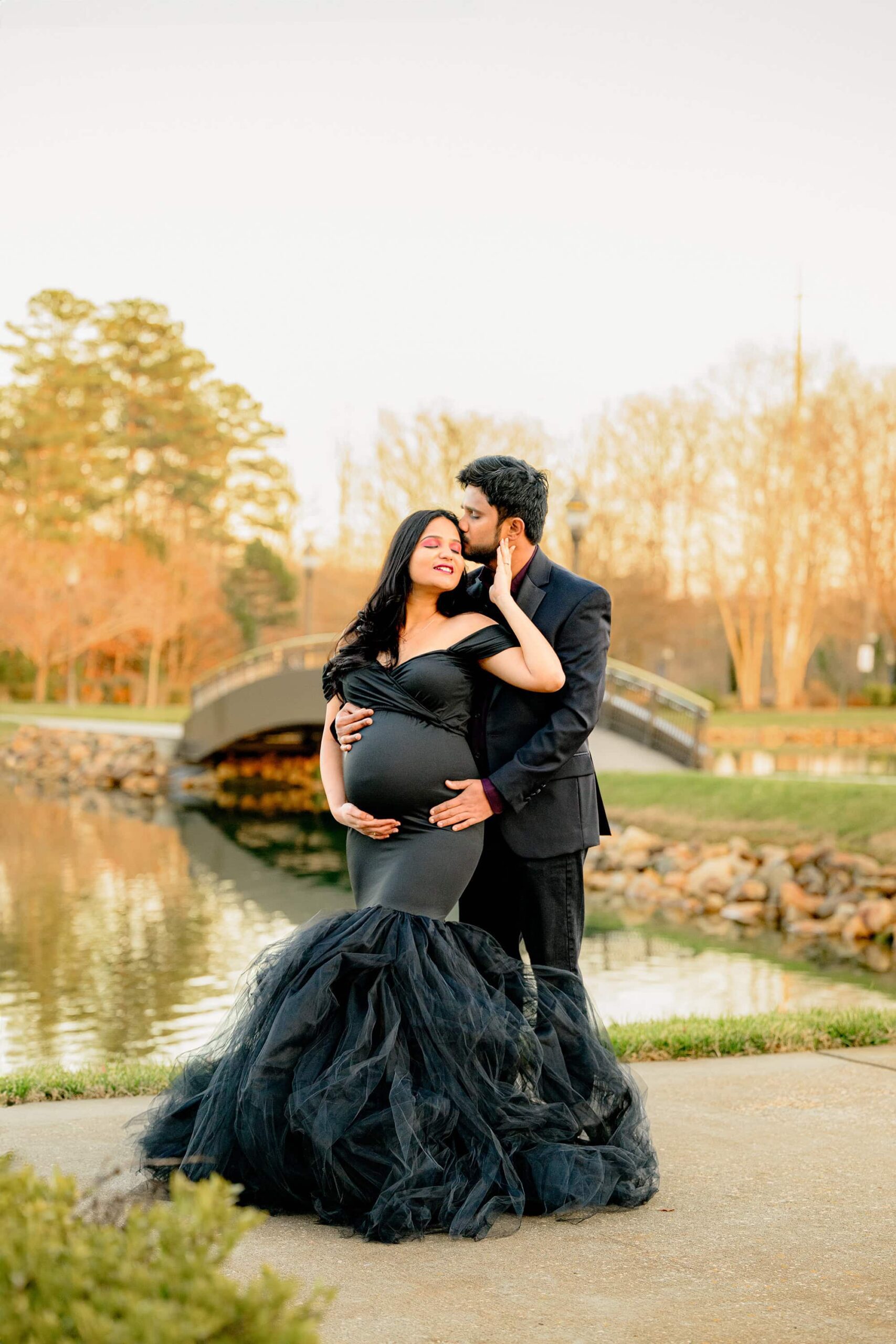 charlotte couple poses together in a warm golden hour embrace in a south carolina location. mom is dressed in black and dad has on suit jacket and shirt