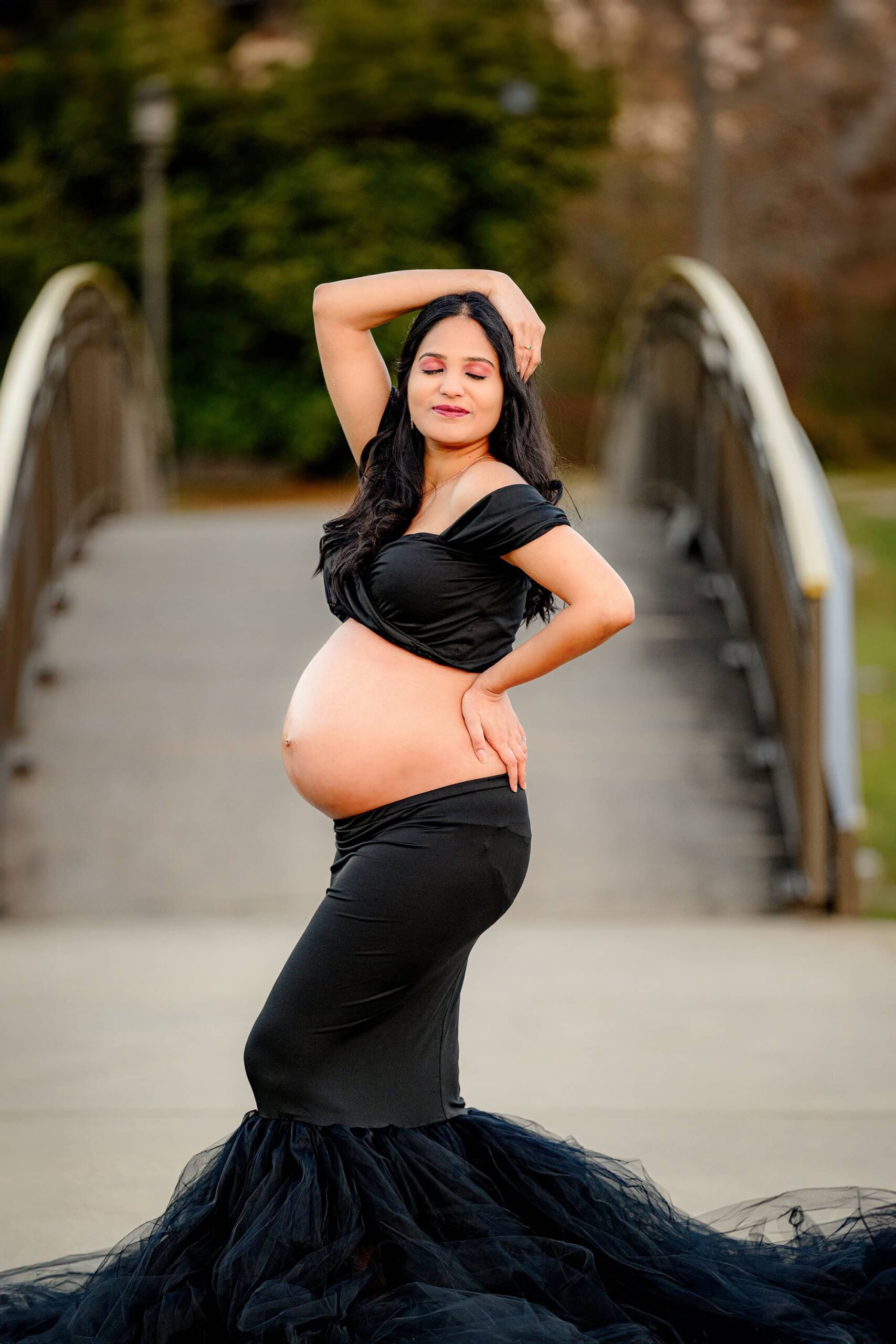 charlotte pregnant mother wearing a black top and dress with black tulle has her belly out as she is posed dramatically